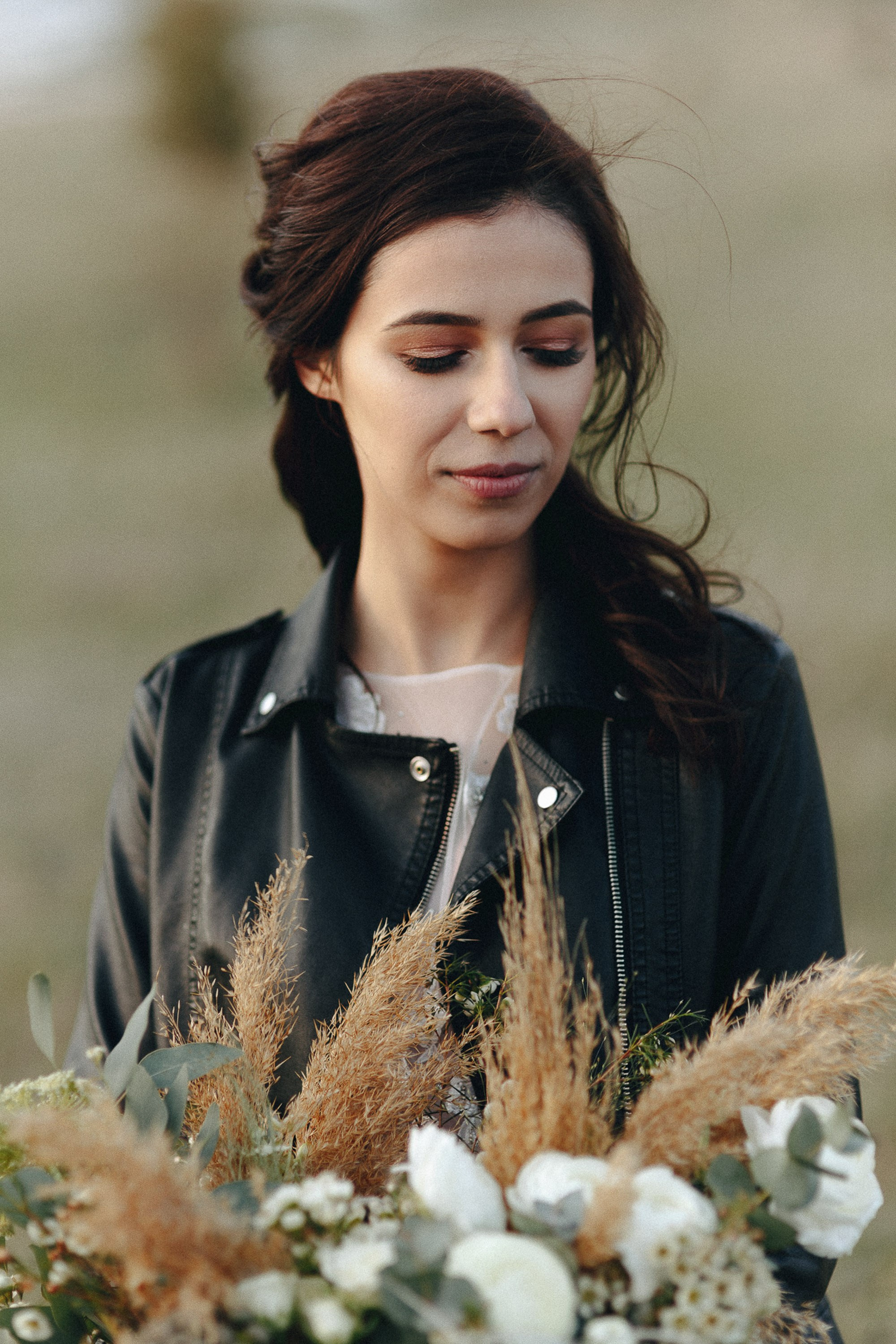 Bride in denim jacket holding bouquet, rustic wedding style