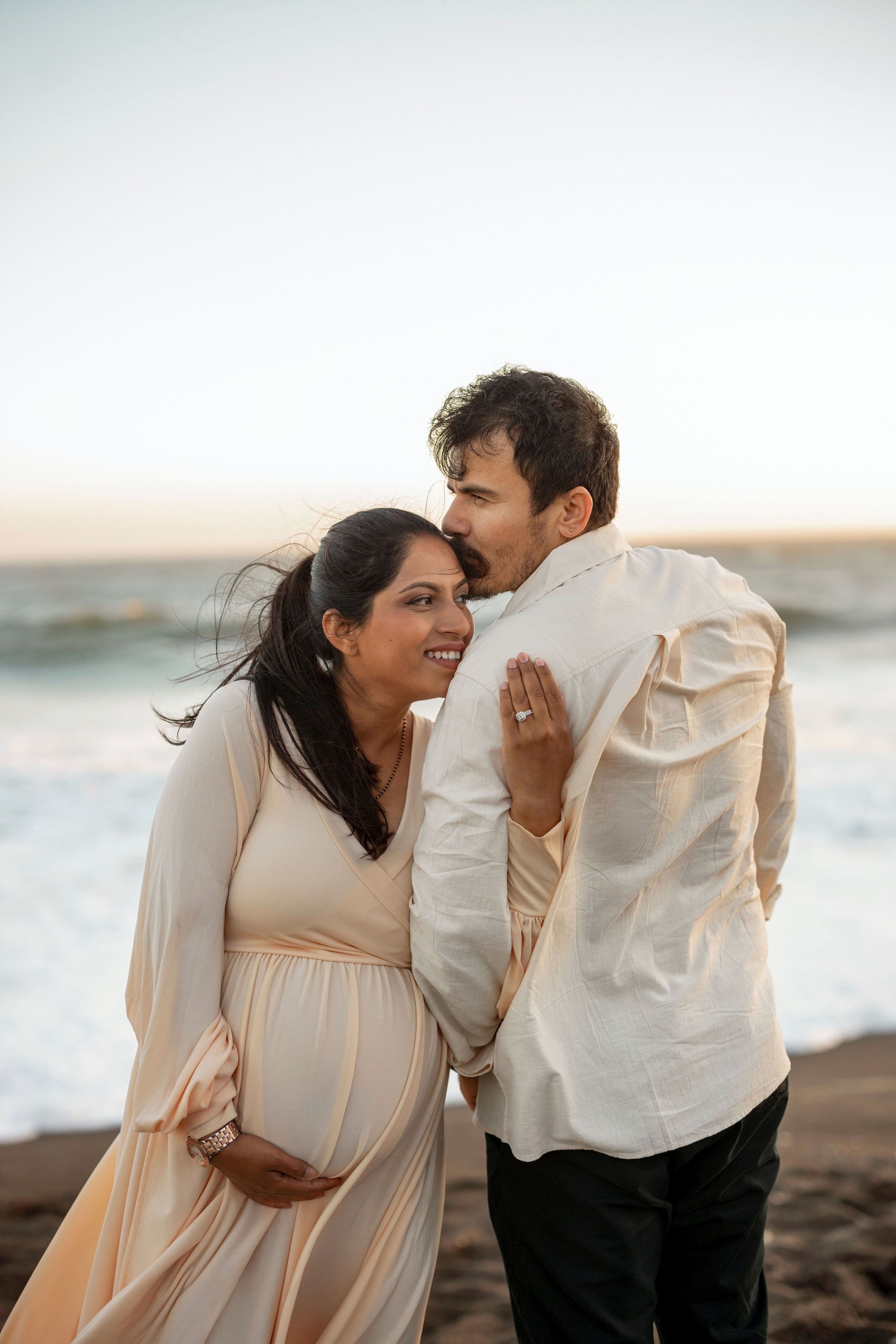 Natural maternity portraits by ocean waves with loving couple