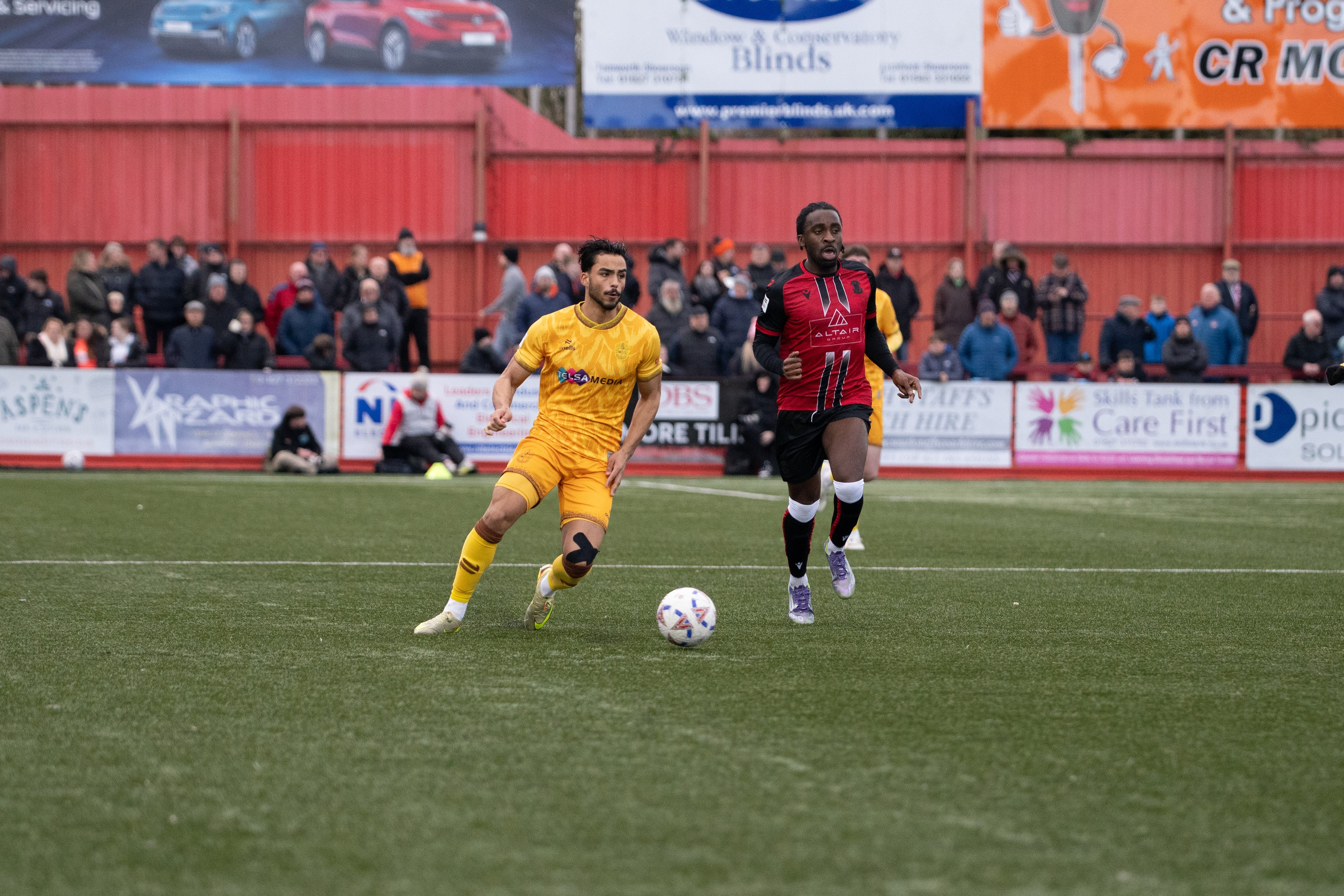 Sutton United’s Junior Eccleston dribbles forward with Tamworth’s Ben Acquaye running behind him.
