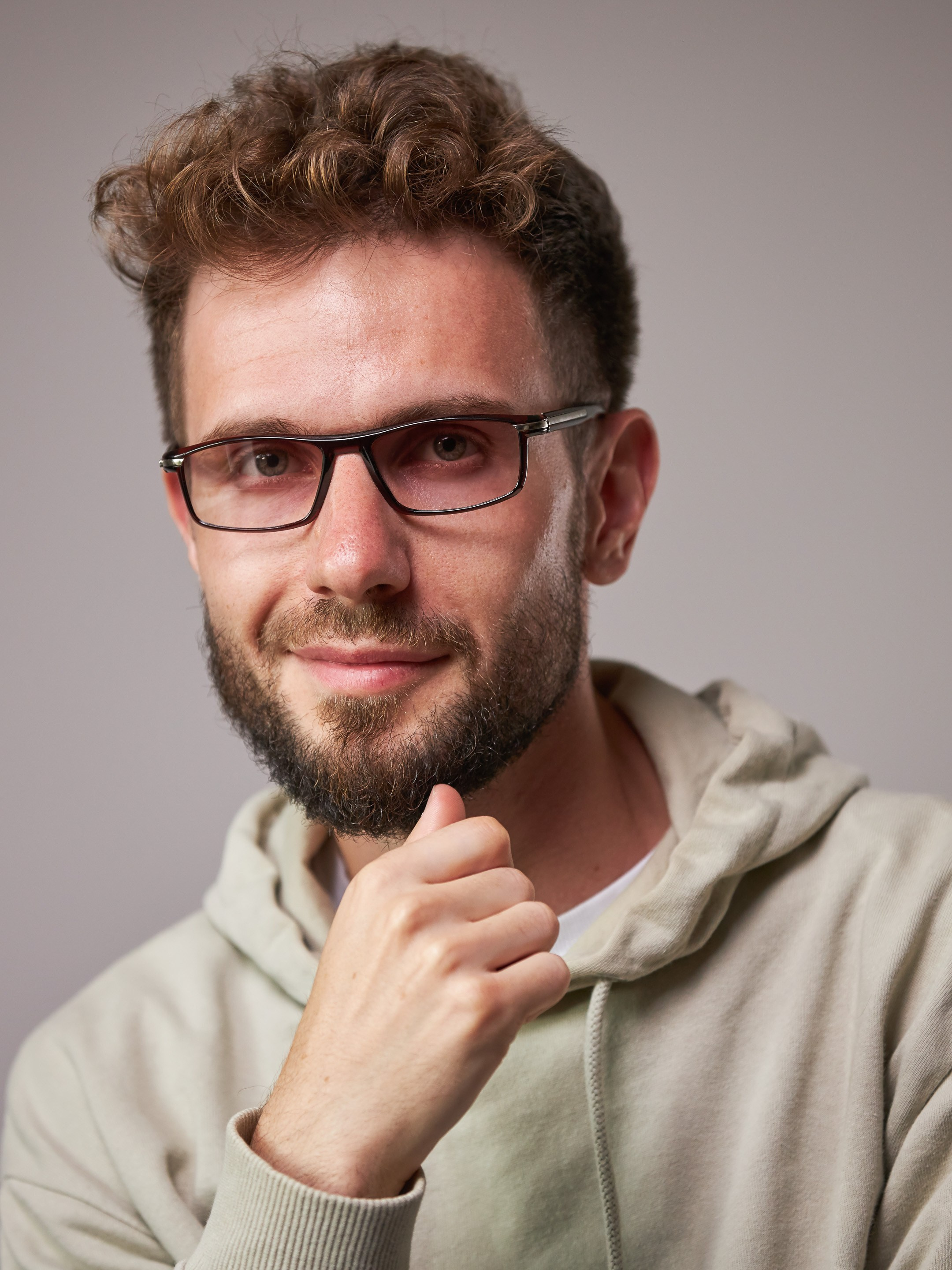 Eyewear model photoshoot - studio portrait of a young man on warm grey background - photographer Andrey Dunin