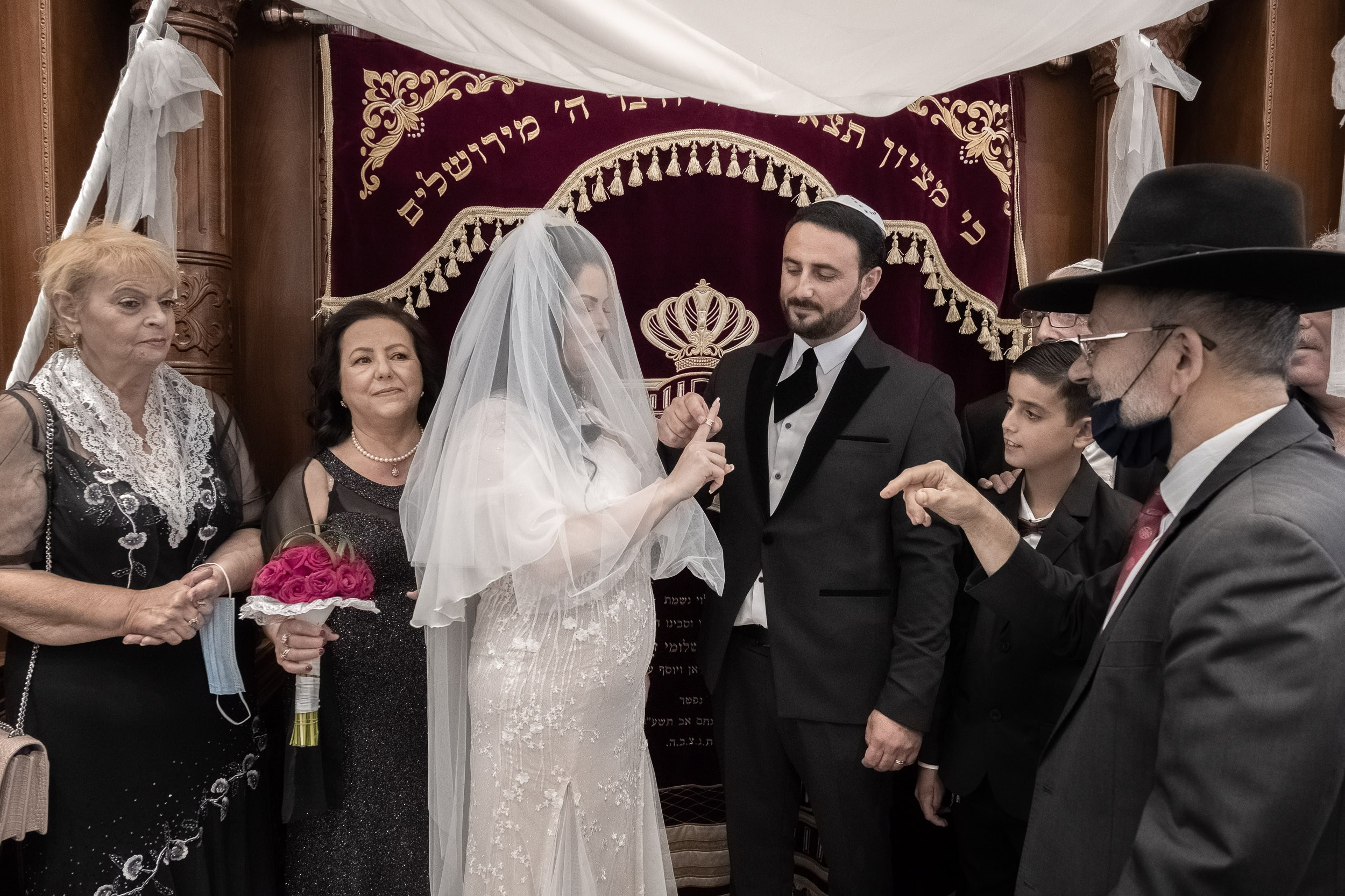 Emil places the wedding ring on Sara’s finger during the synagogue ceremony