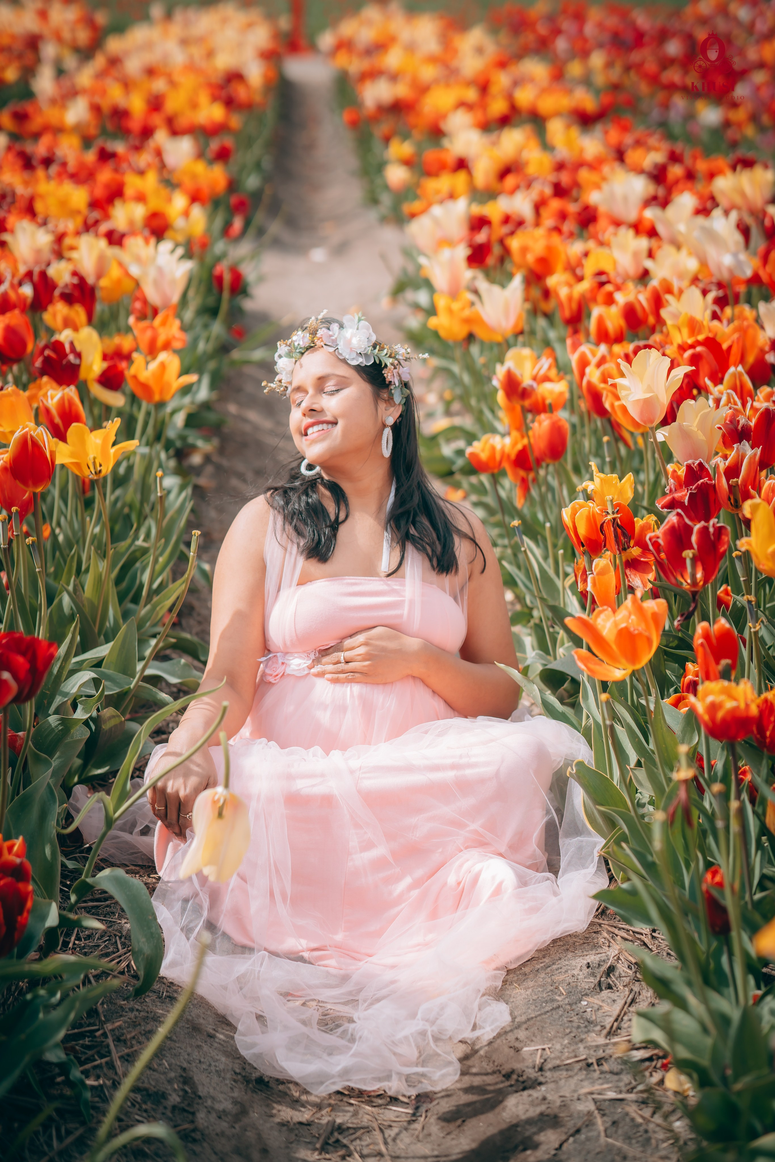 A pregnant woman sitting and soaking in sun in tulip fields in netherlands