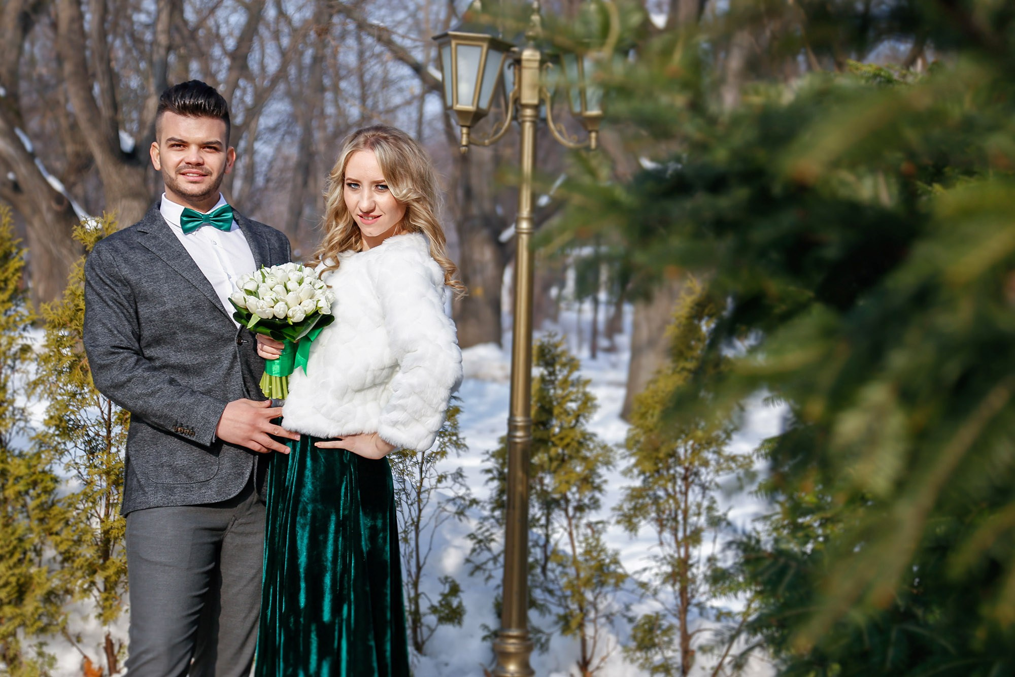 Smiling newlyweds photographed in a snowy natural park, a fairy-tale setting during a winter civil ceremony photo shoot.