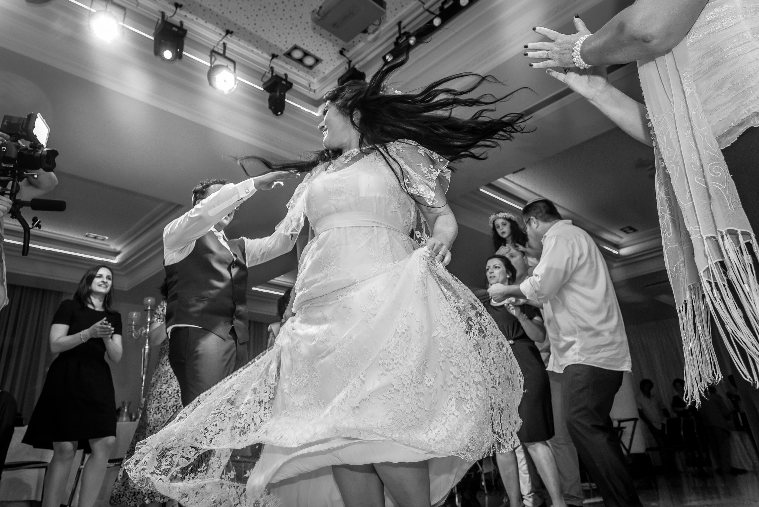 Bride spinning in a white dress on the dance floor during a high-energy wedding reception in Israel