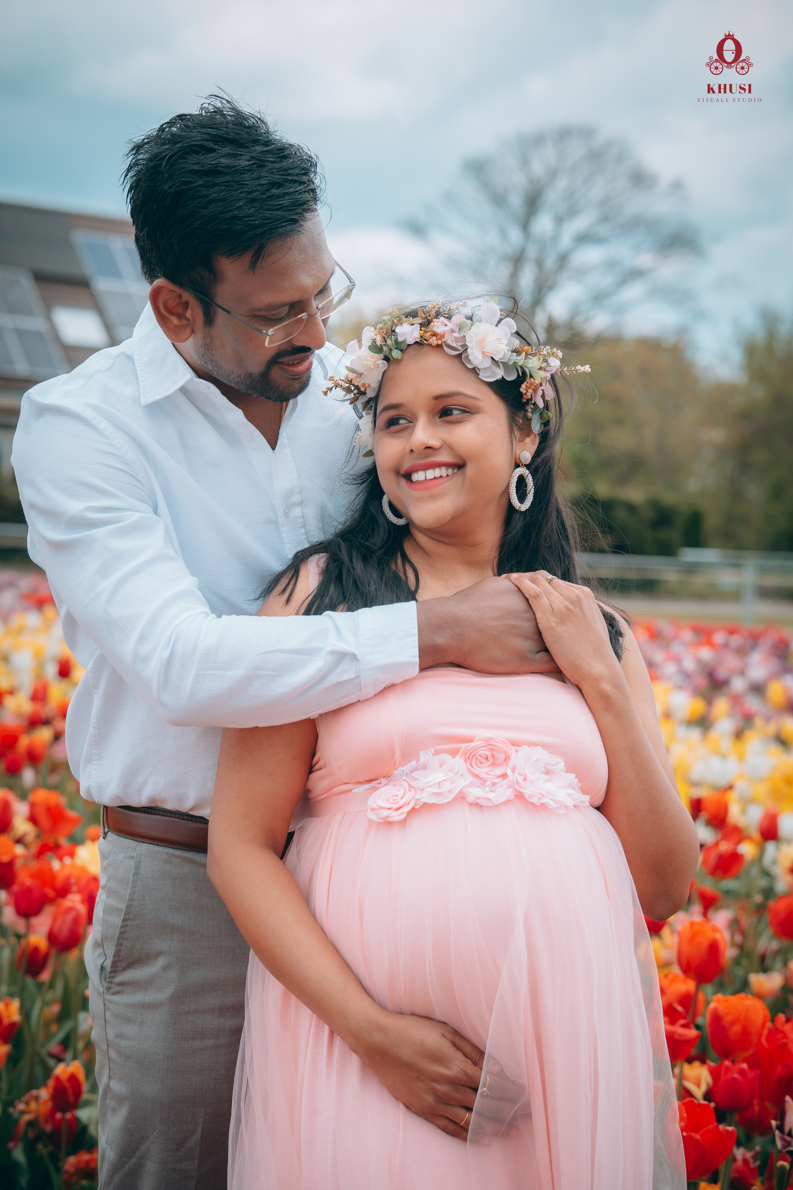 A man holding her pregnant wife from behind in a tulip fields in netherlands