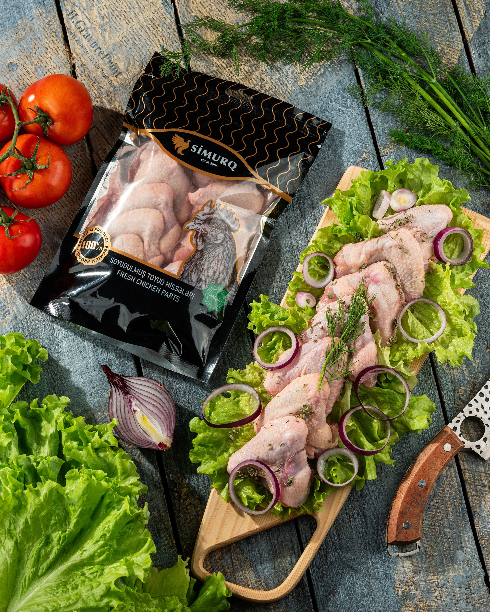 Simurq soyudulmuş toyuq hissələri, yaşıl yarpaqlar və qırmızı soğan dilimləri ilə taxta fon üzərində