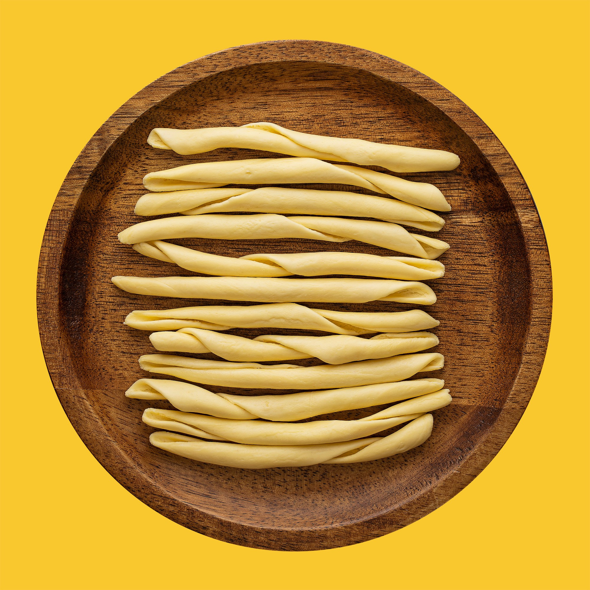 Photographer Roman Djuzev - Fileja calabresi pasta on a wooden plate, shot in high key, on a white background.