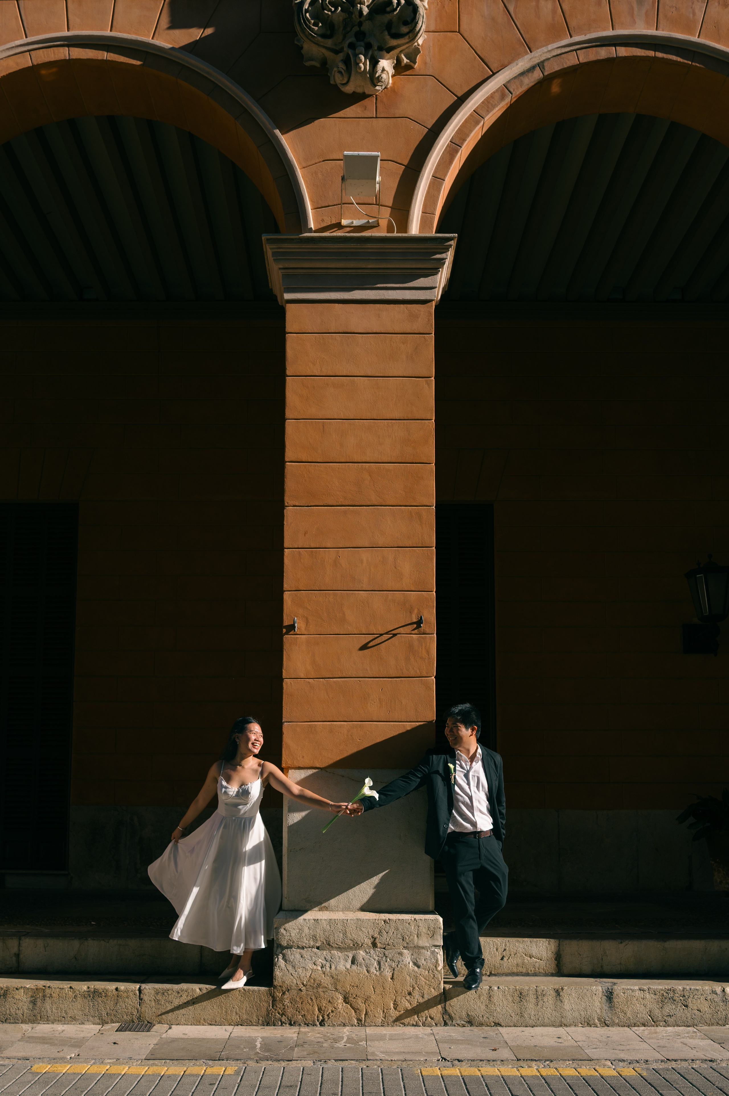 Wedding couple walking through sunlit arcades in Palma de Mallorca