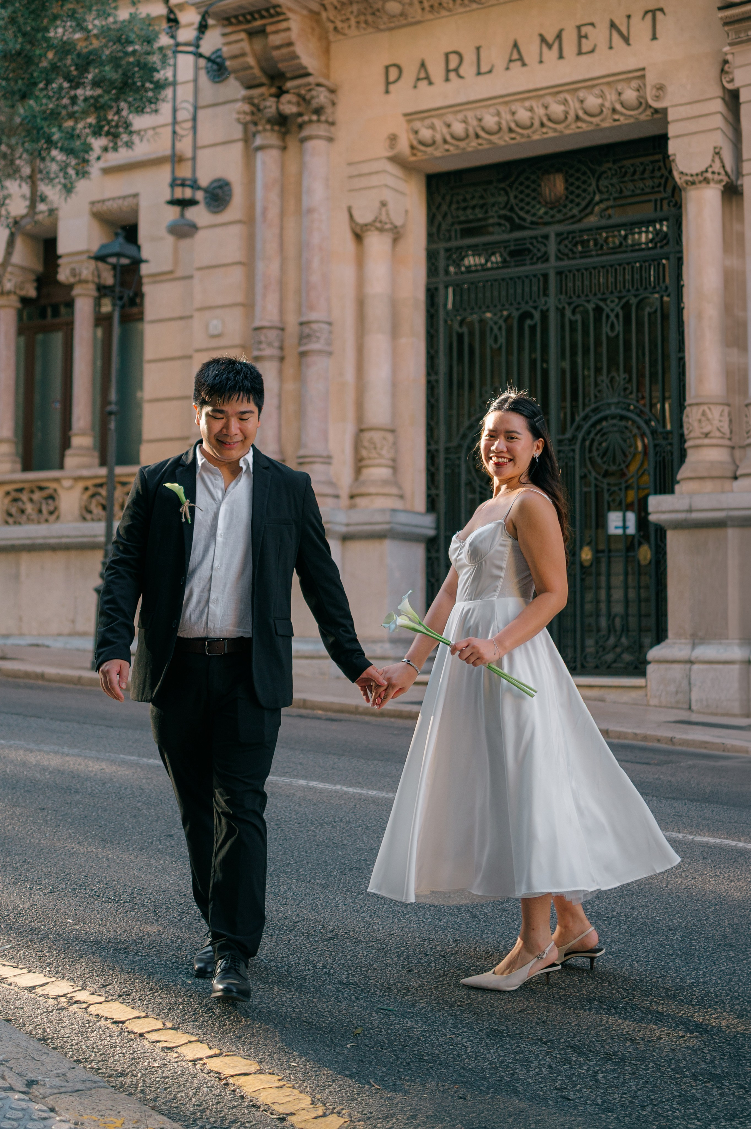 Smiling wedding couple holding hands in front of the Parliament of Mallorca
