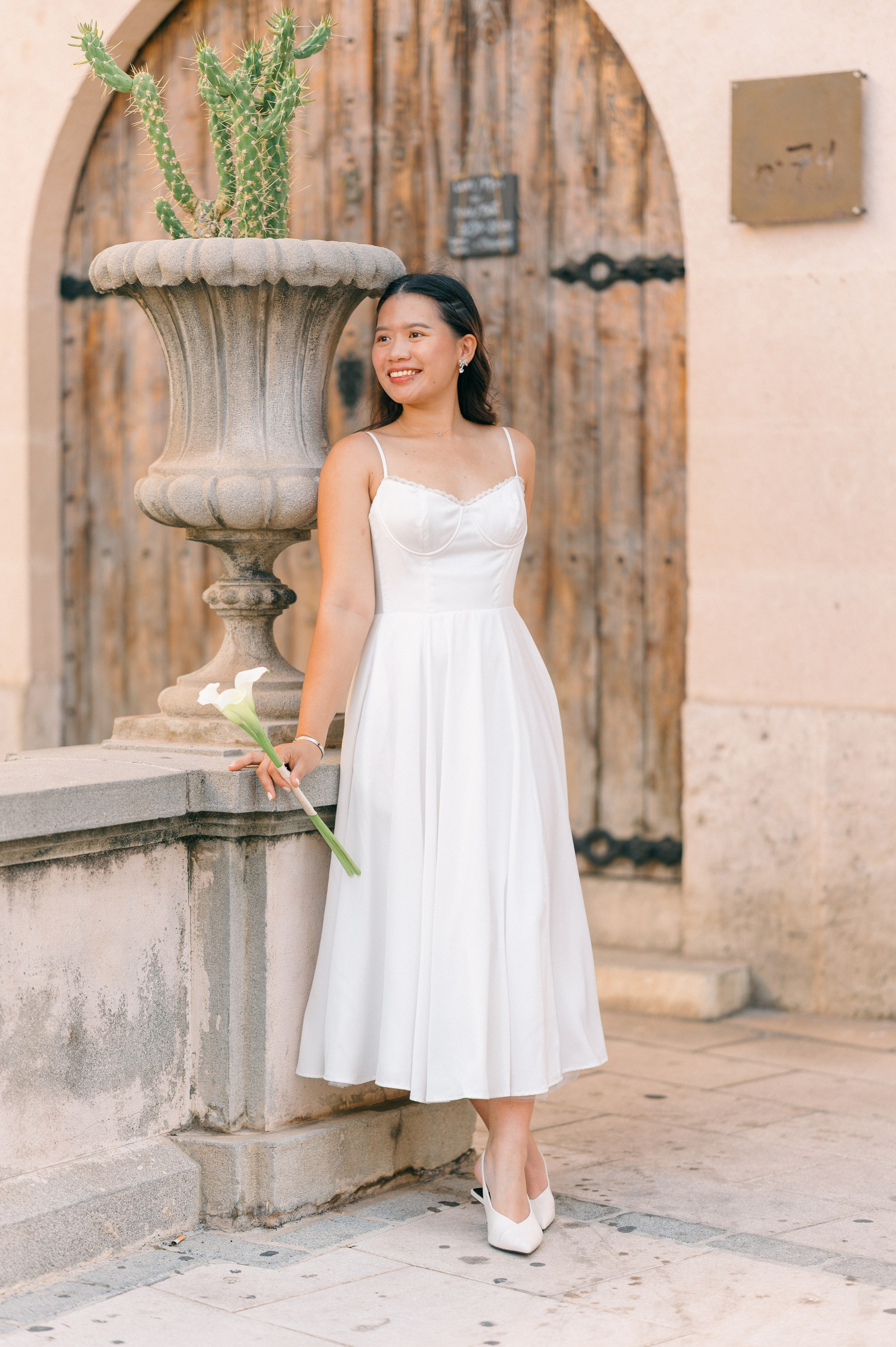 Bride holding white flowers beside historic architecture in Palma Mallorca