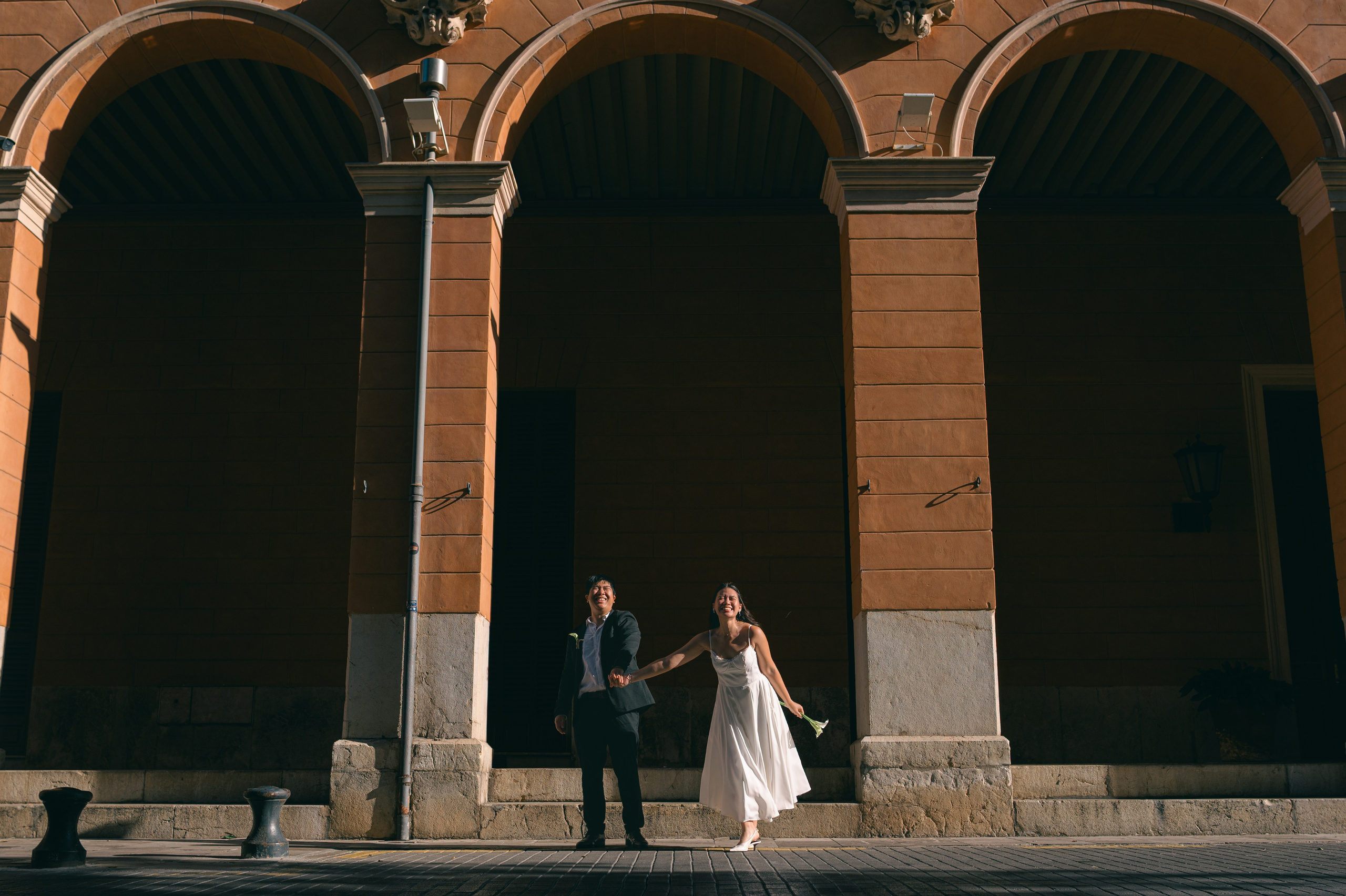 Cinematic wide portrait of a couple beneath Palma’s historic arcades