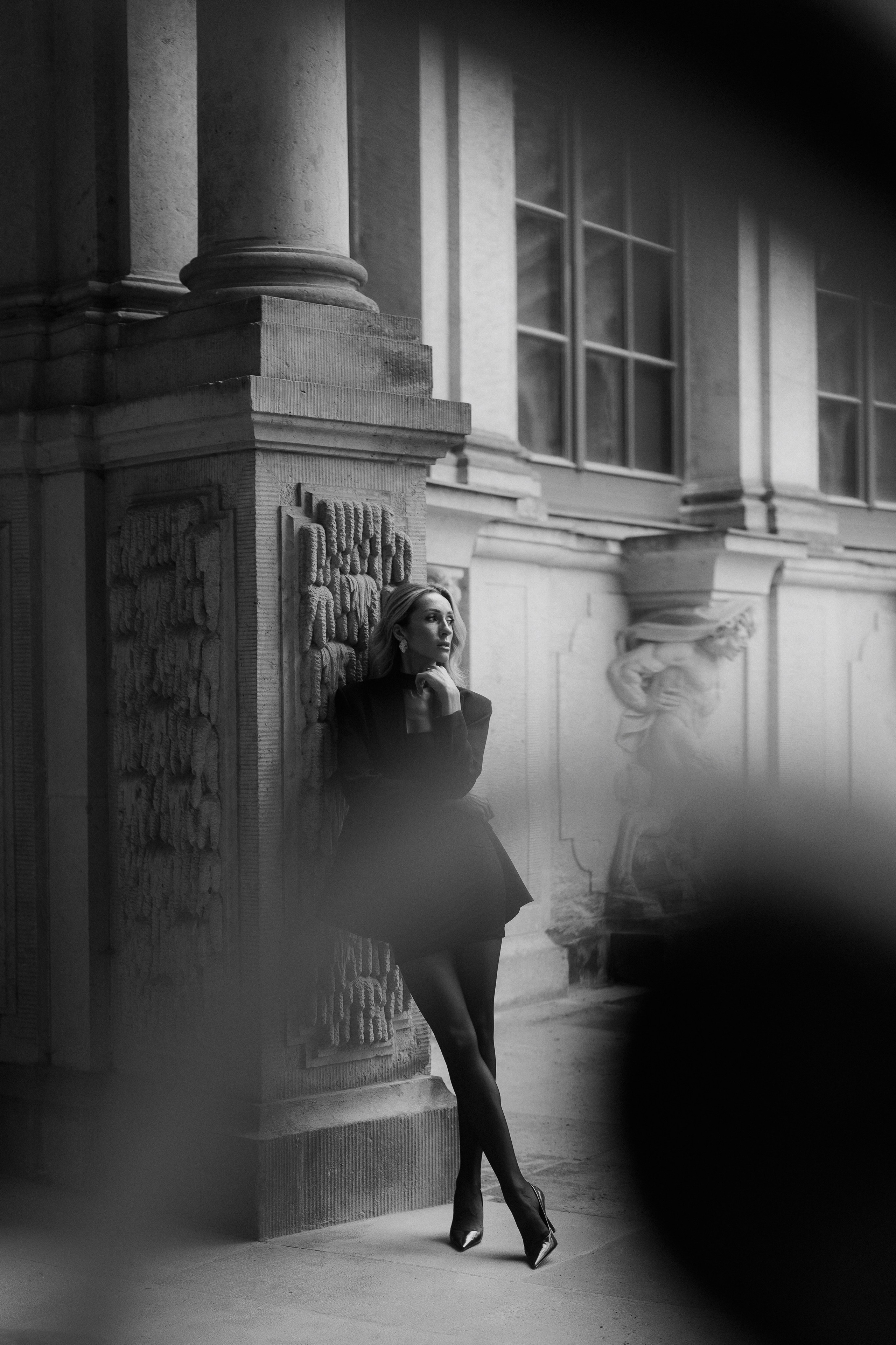 Moody black and white portrait of a woman posing by a historic stone column in Dresden, Germany. Timeless female portrait photography inspired by editorial fashion, available in Dresden, Leipzig and Wurzen. Атмосферный чёрно-белый портрет девушки у исторической каменной колонны в Дрездене, Германия. Вневременная женская портретная фотография в стиле fashion editorial в Дрездене, Лейпциге и Вурцене.