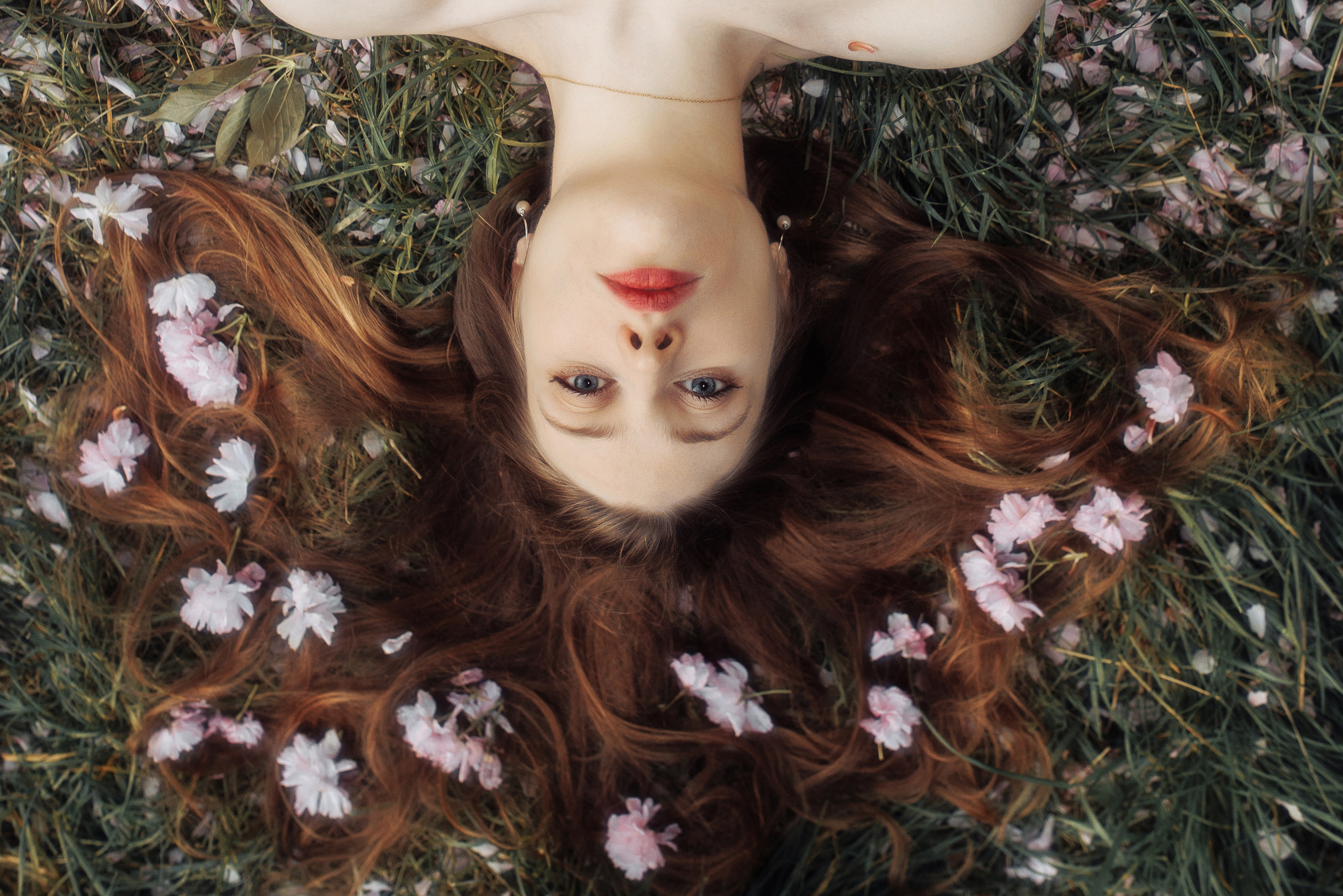 Девушка лежит на траве, её распущенные волосы украшены цветами. Фотография для афиши