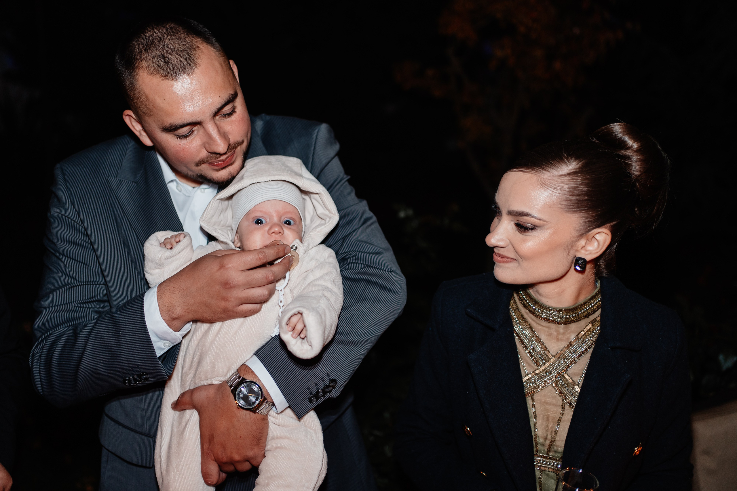 Instantaneu plin de tandrețe dintre părinți și bebeluș în ziua botezului, realizat în Craiova. Fotografie profesională de botez, capturând emoțiile autentice ale familiei într-un decor luminos și cald