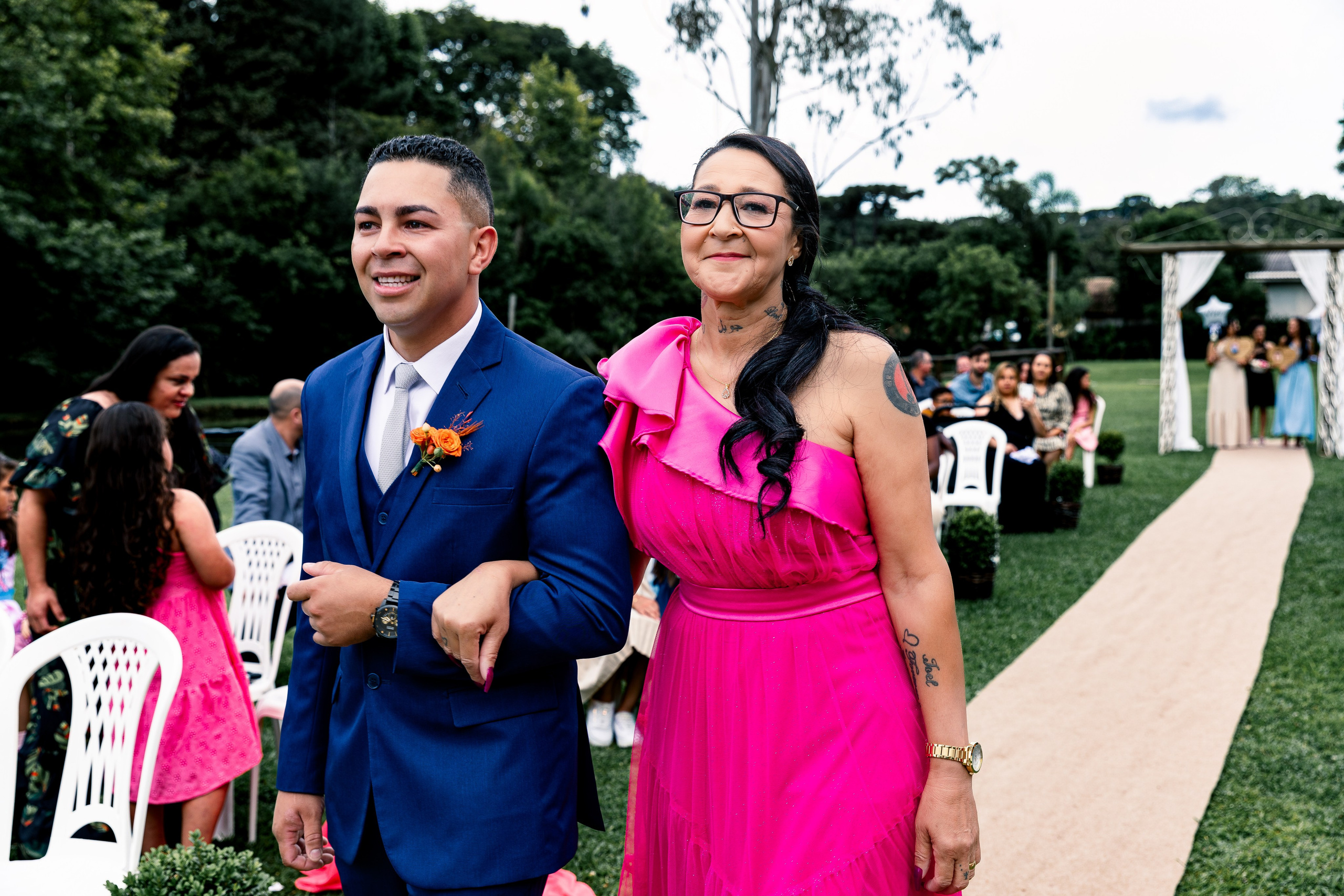 Noivo entrando com sua mãe no início da cerimônia de casamento, momento de honra e emoção.