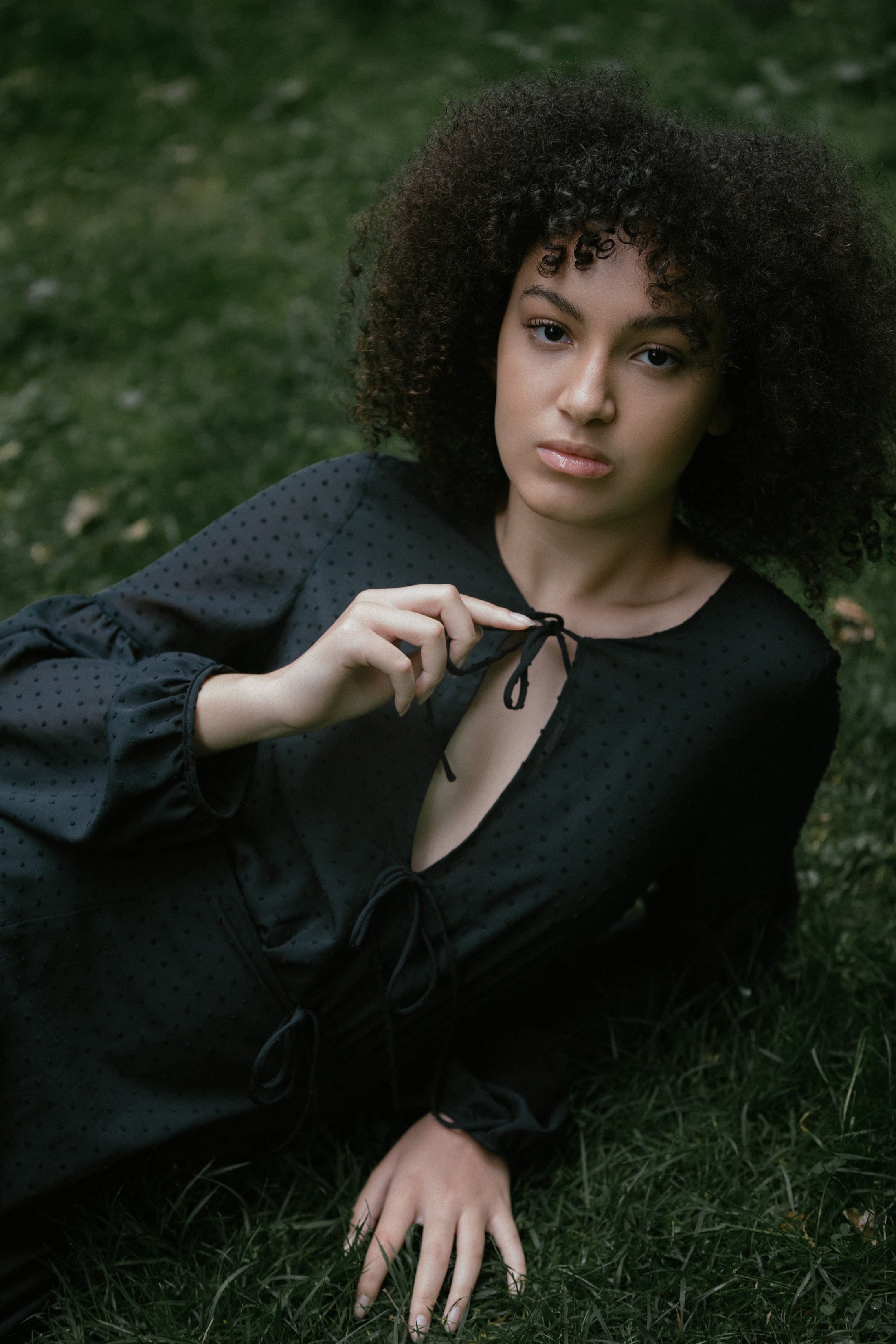 Frau hält Kleiderband, liegt im Gras, ruhiger Blick