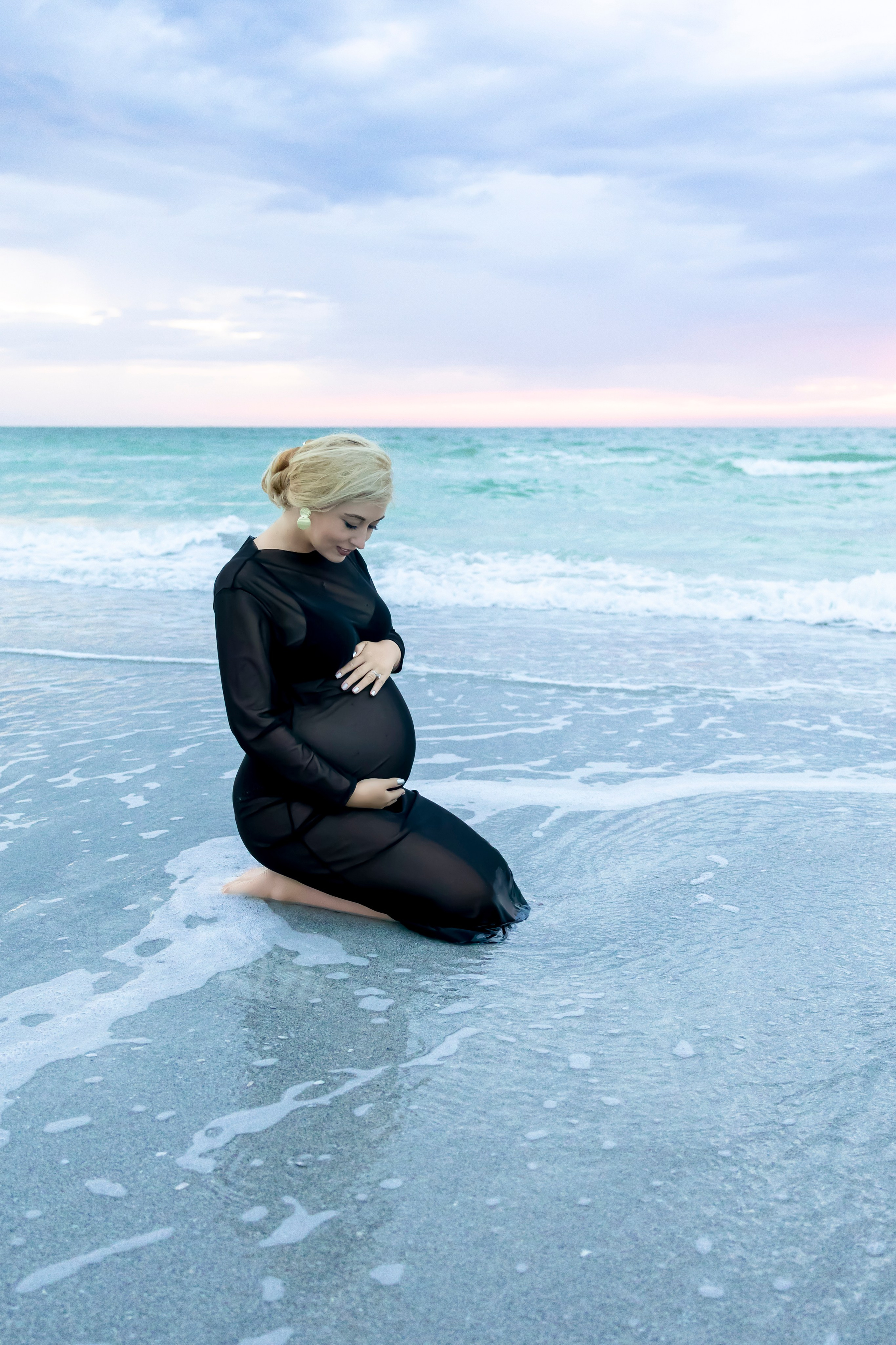pregnant woman siting in the ocean waives