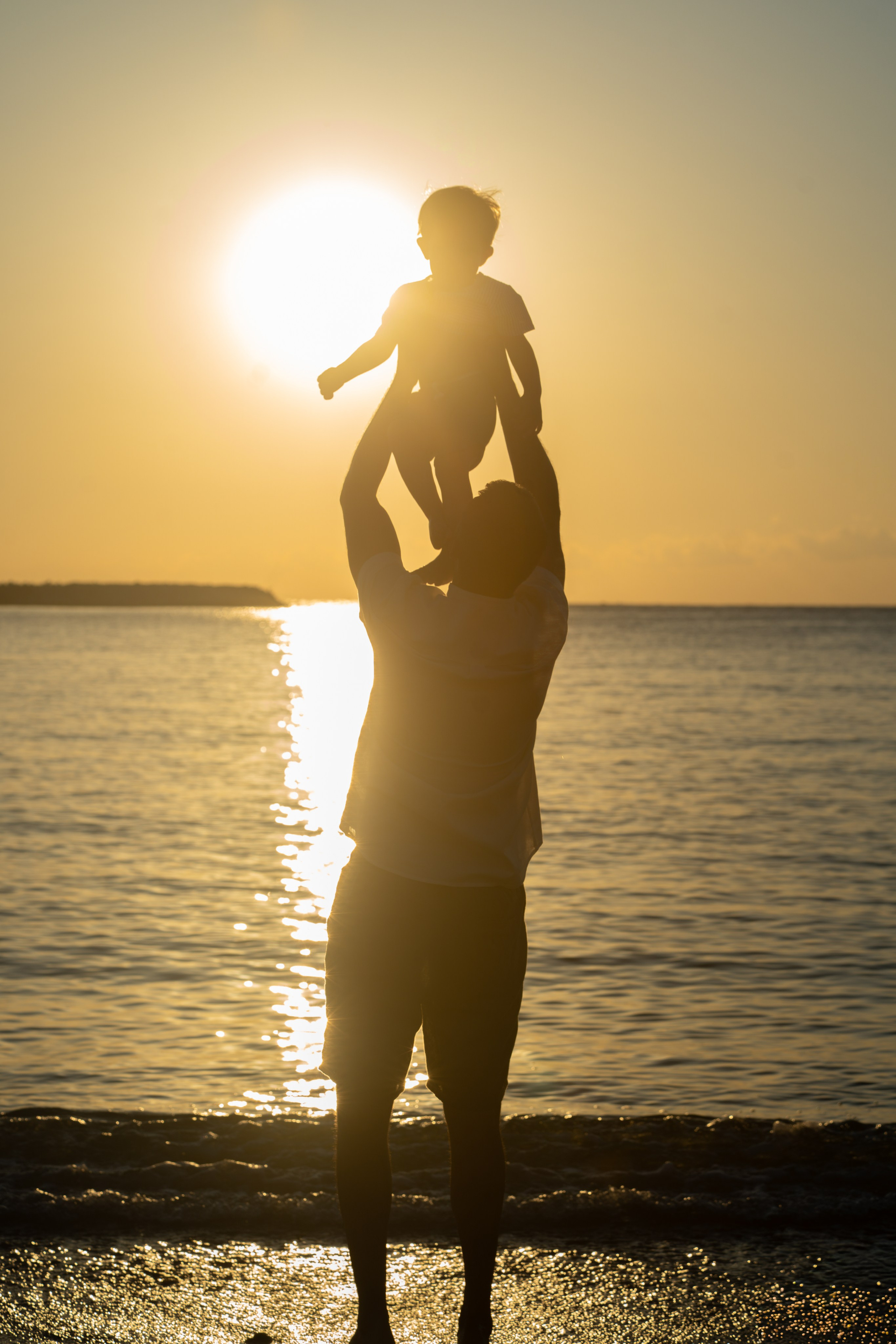 tata care se joaca cu copilul in razele soarelui la rasarit