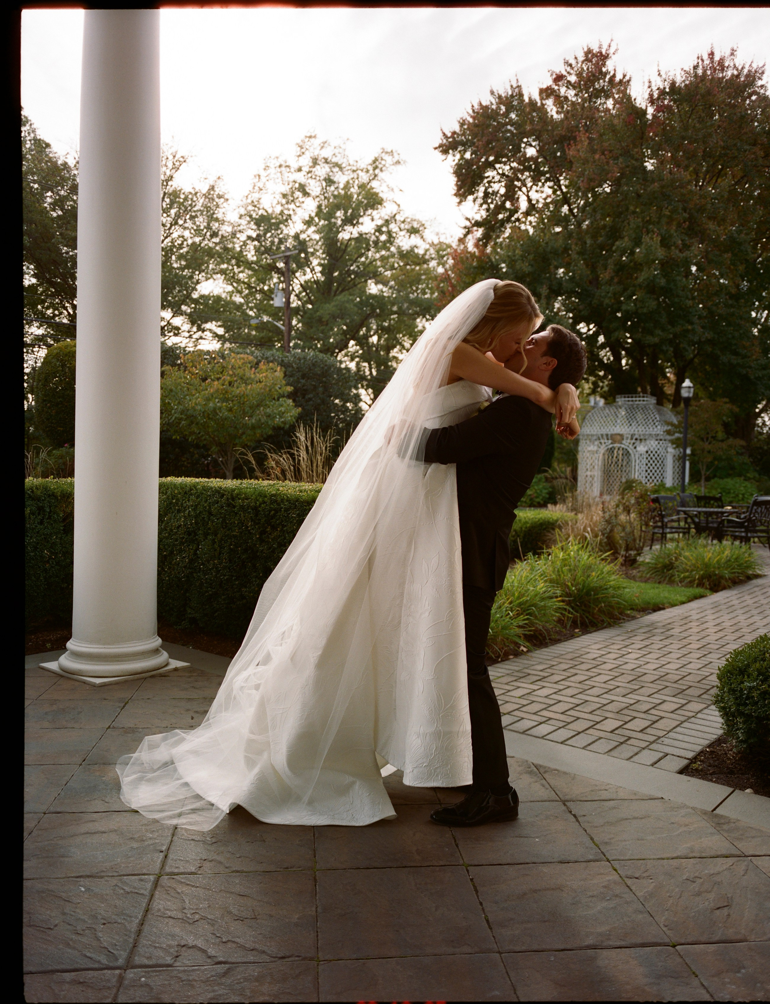 Emily and Michael sharing a kiss beneath the columns at The Rockleigh
