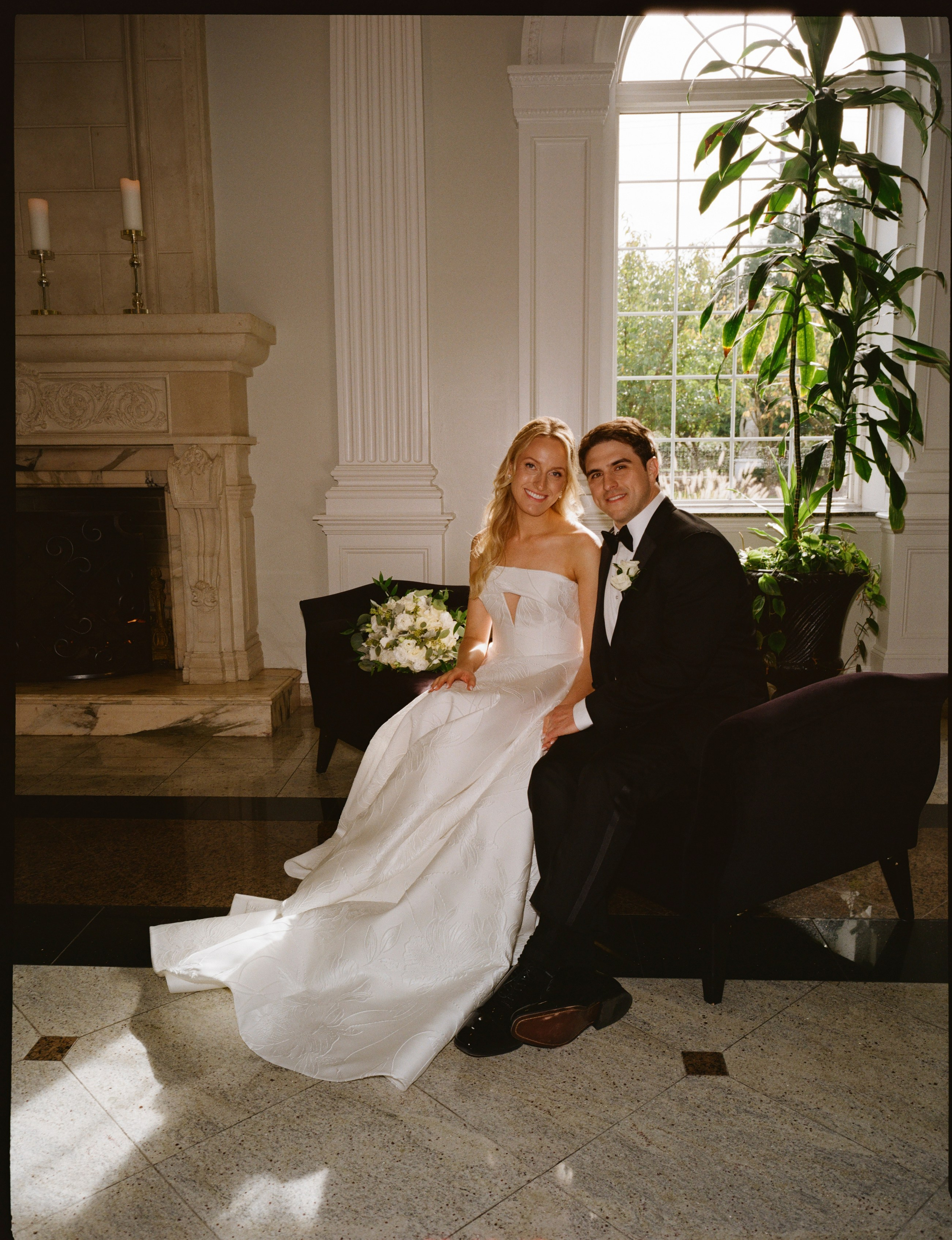 Romantic indoor wedding portrait of the newlyweds relaxing together on a sofa