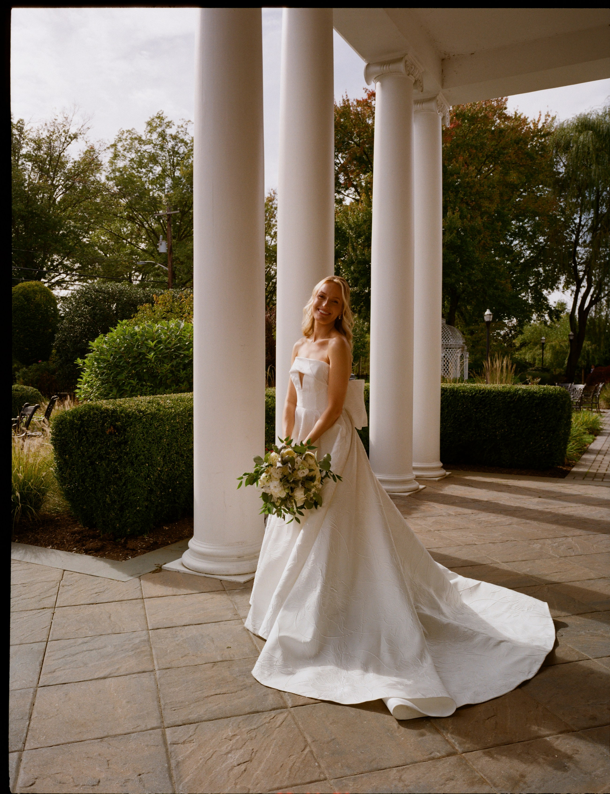 Full-length film bridal portrait beside the white columns at The Rockleigh