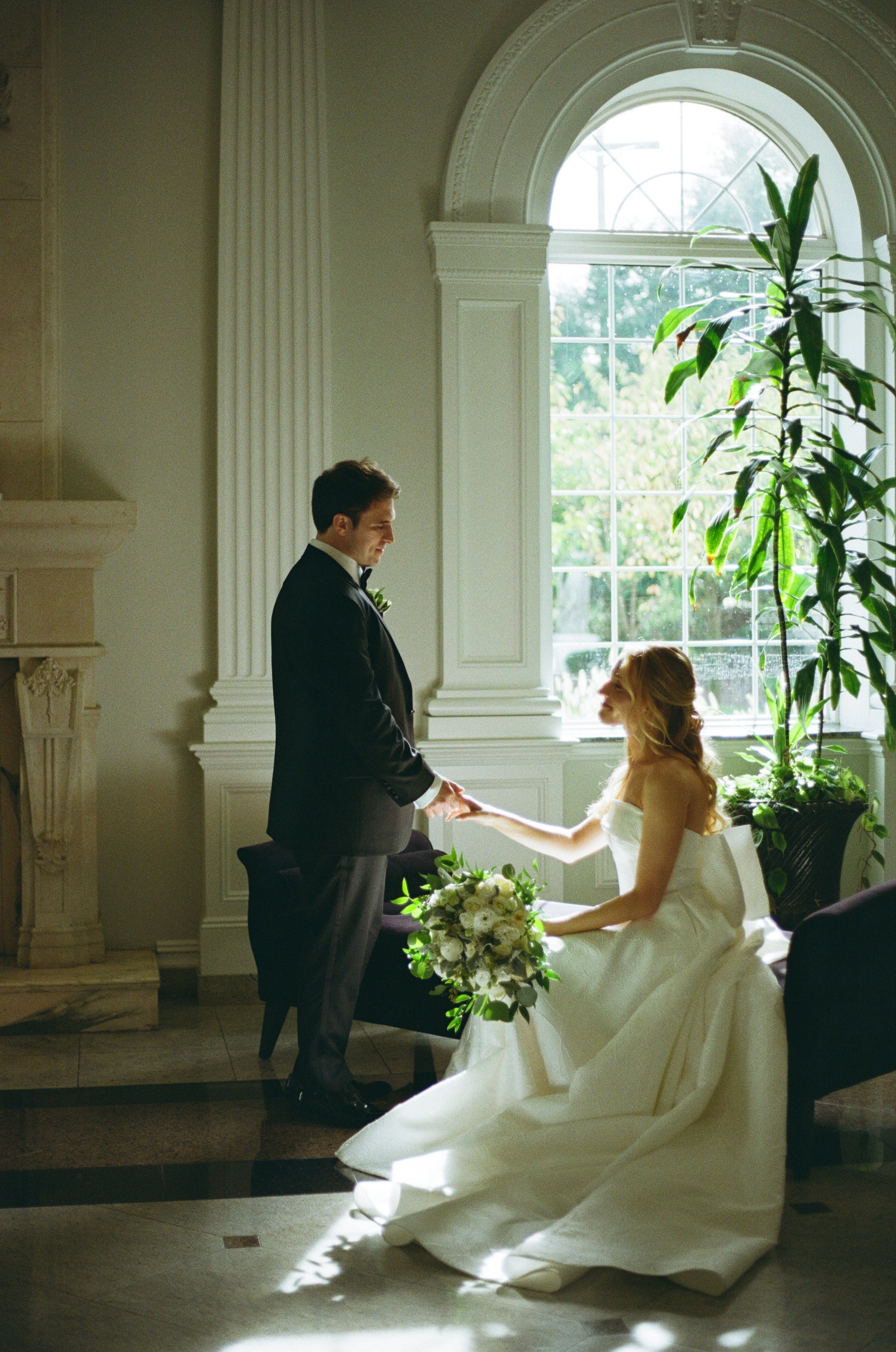 Emily and Michael sitting together beside an arched window at The Rockleigh