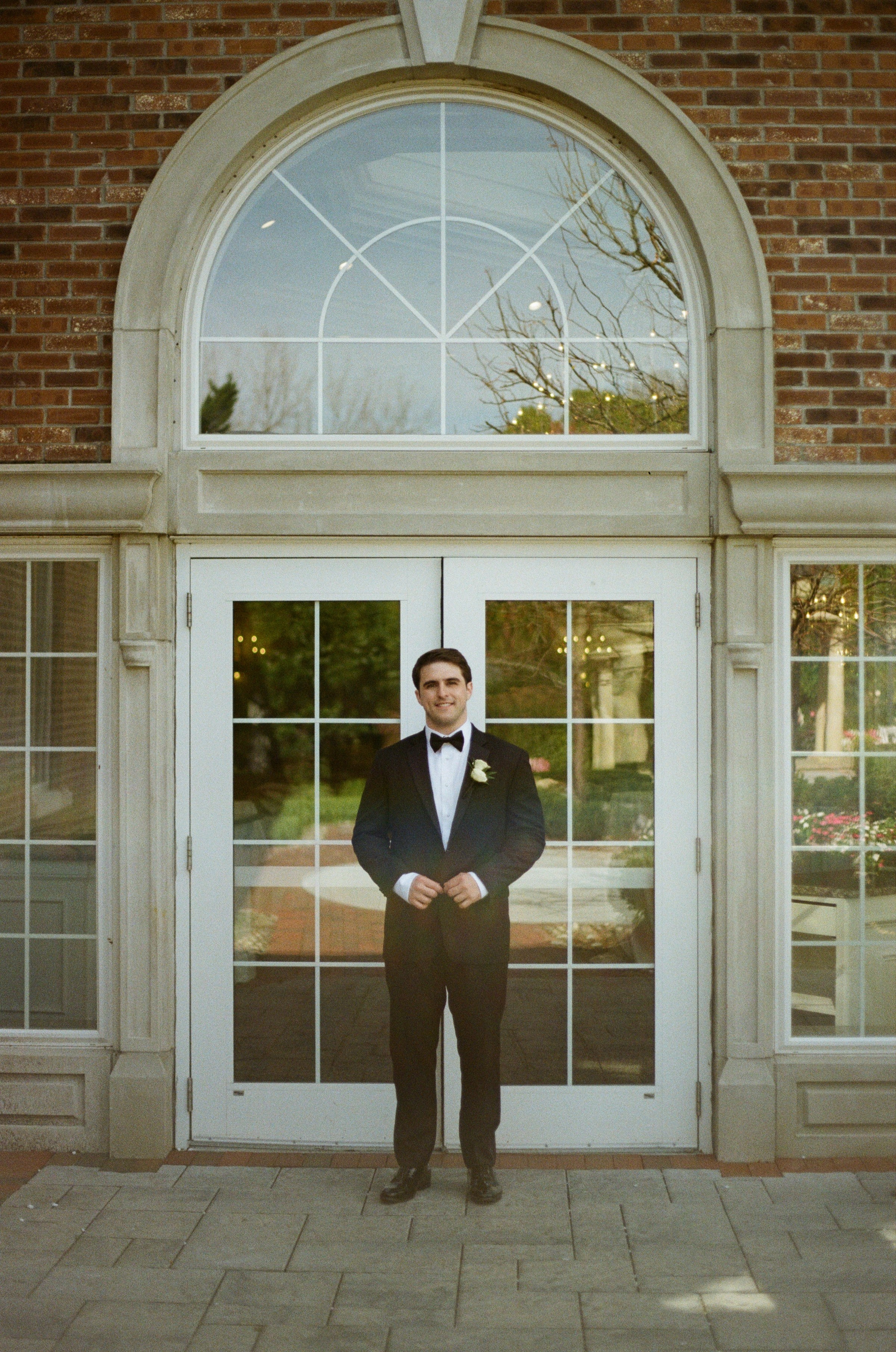 Editorial groom portrait beneath an arched doorway at The Rockleigh