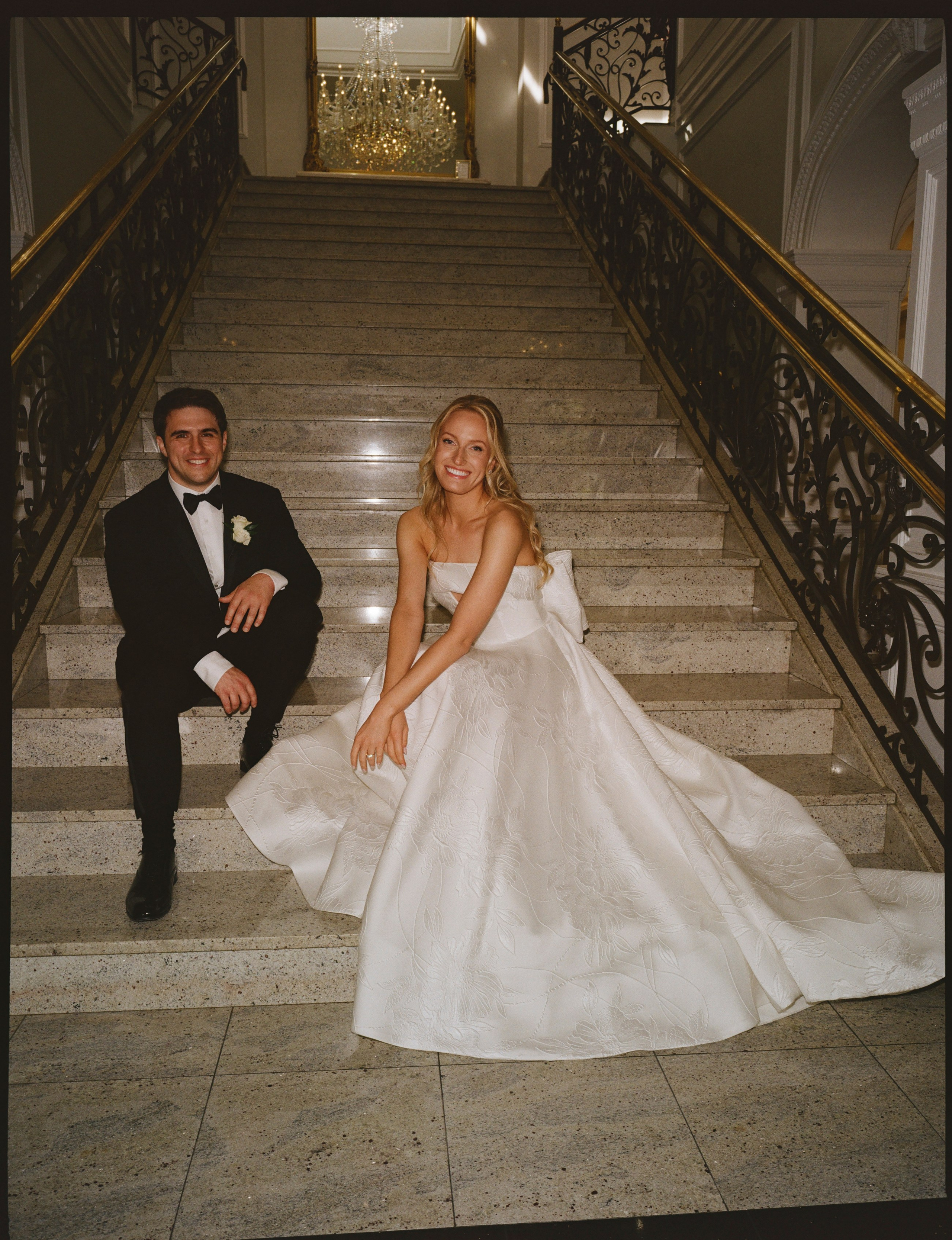 Emily and Michael posing beside the grand staircase at The Rockleigh