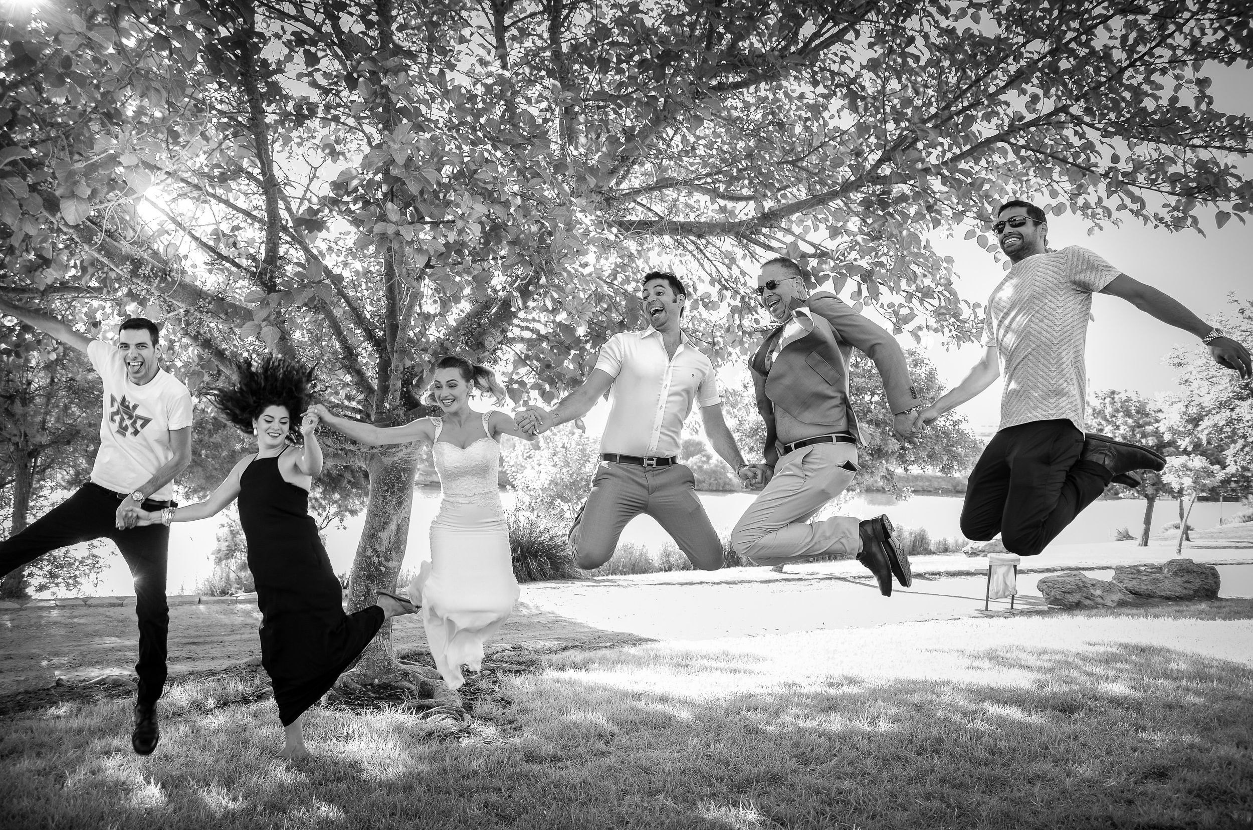 Bride, groom, and bridal party jumping together during a wedding photo session in Israel
