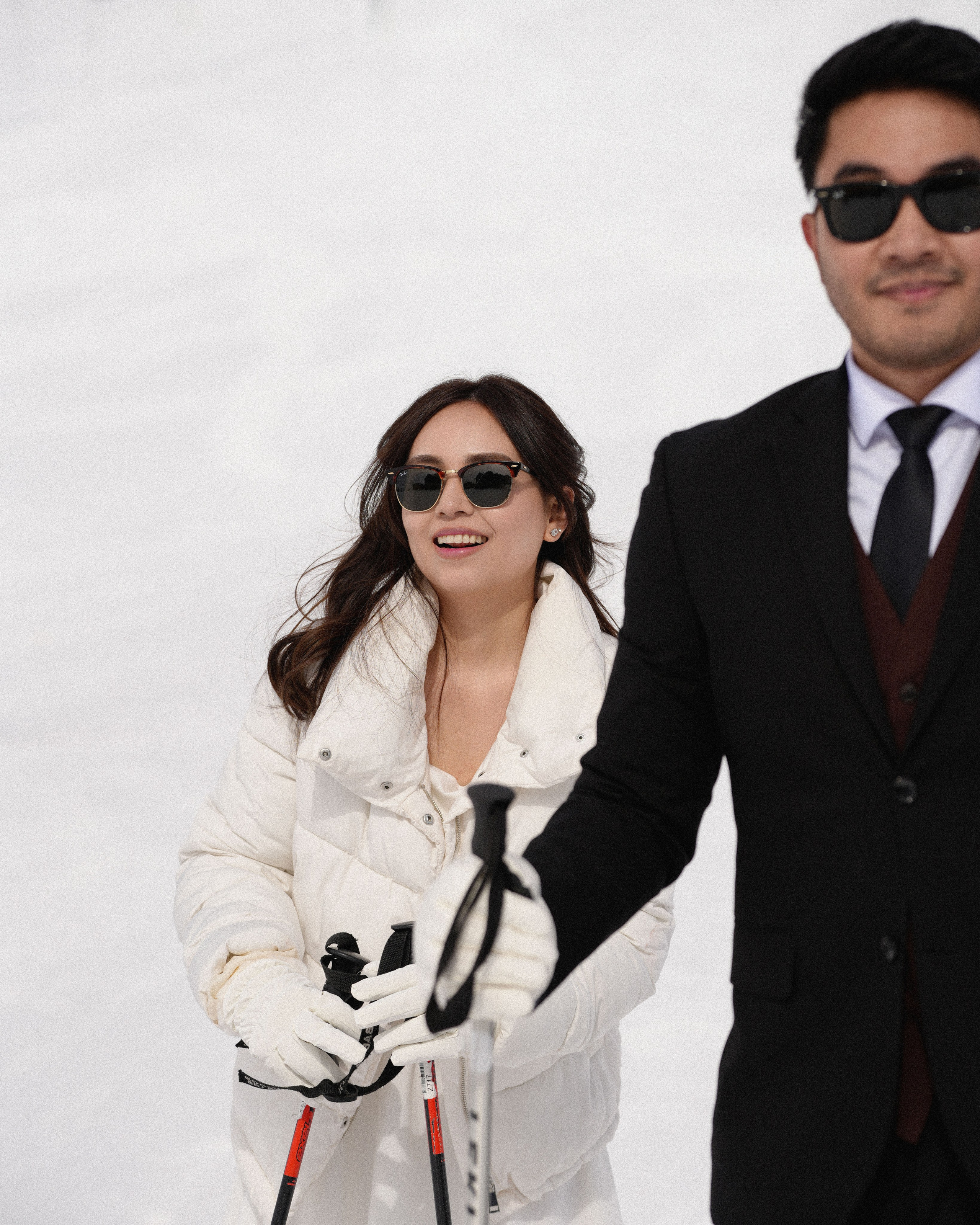 Couple laughing while skiing down the slope during engagement session