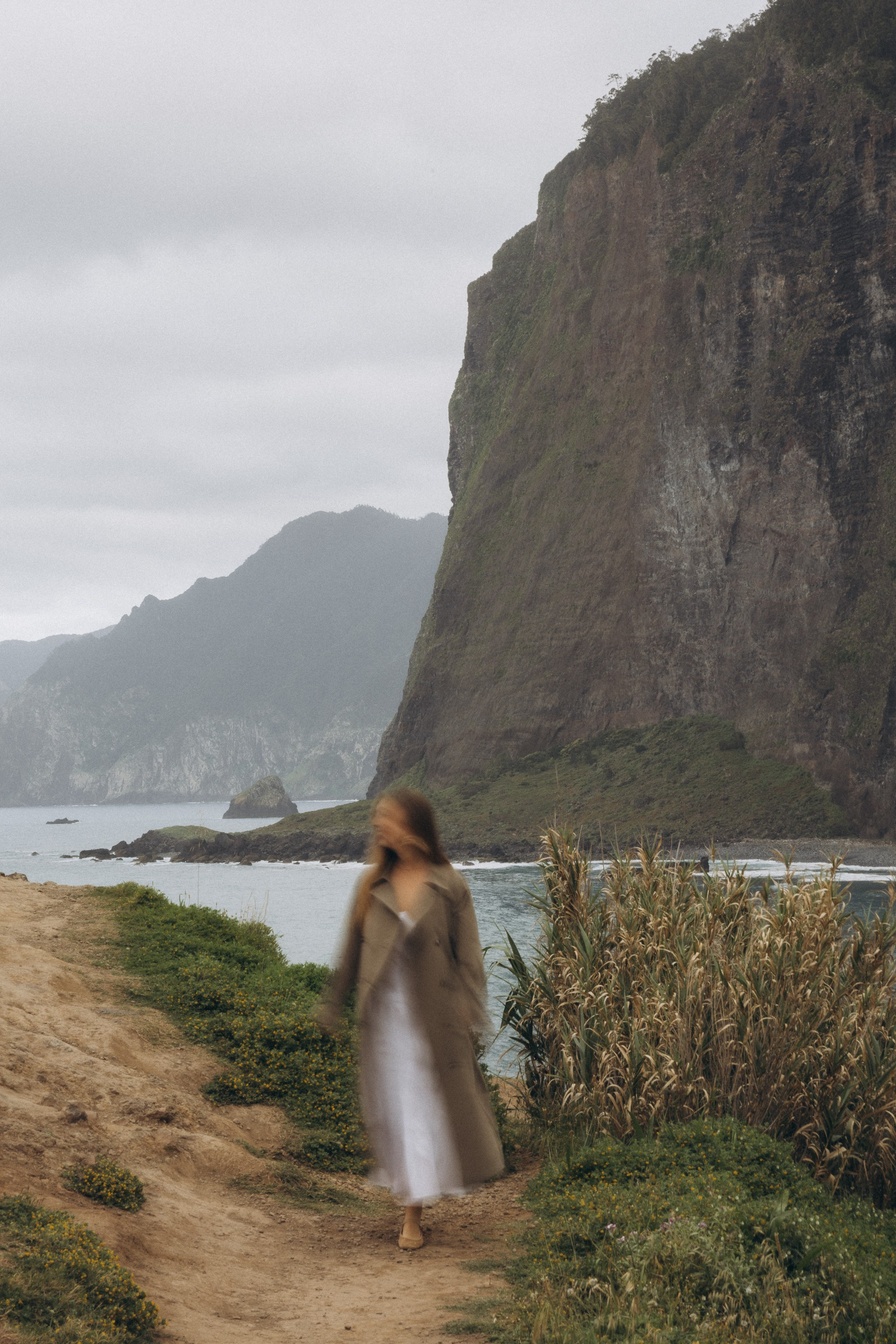 Beautiful engagement moment by the ocean in Madeira, Portugal, as one partner kneels to propose while waves crash in the background.