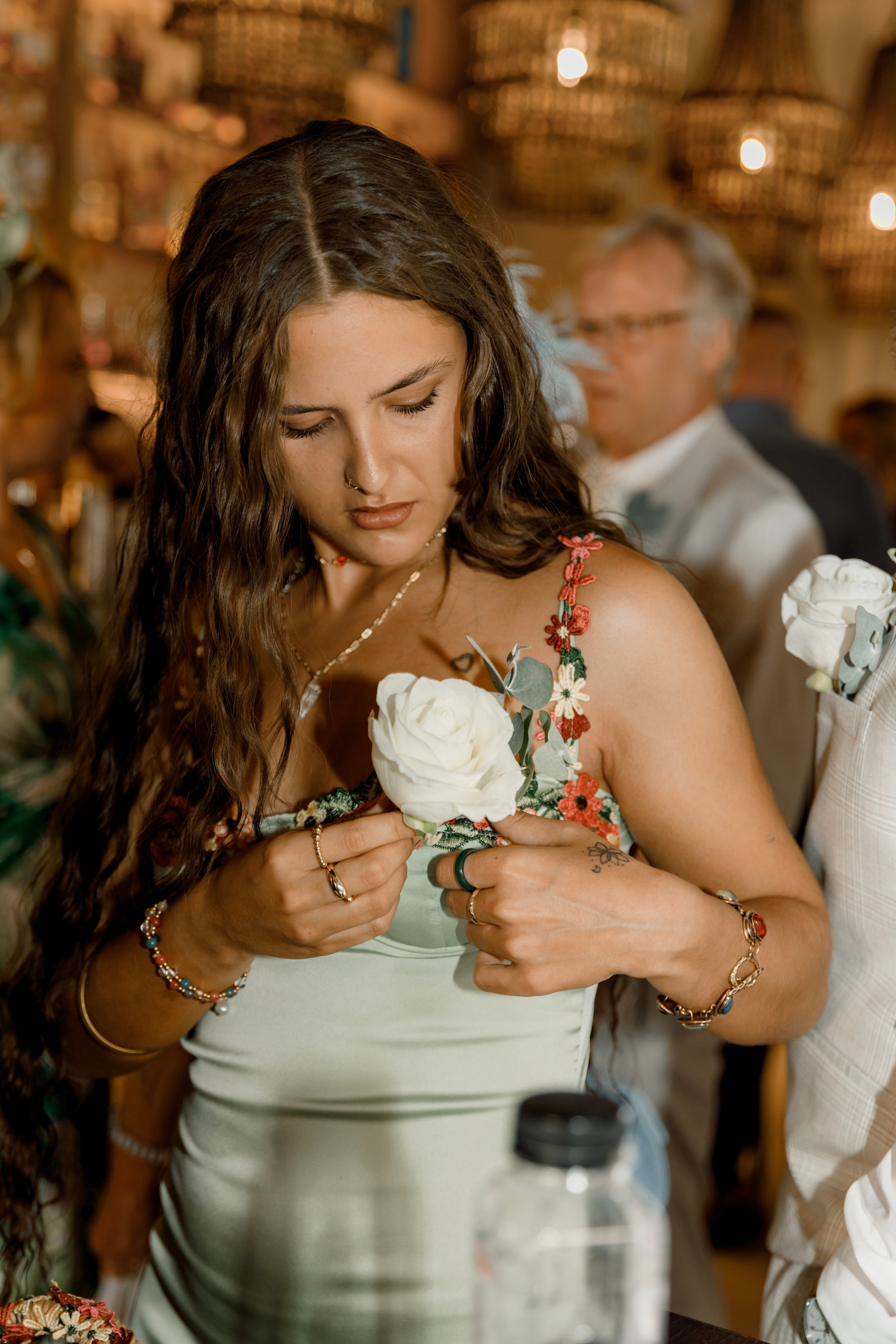 The groom's sister is putting a boutonniere on the dress in Lindos, Greece