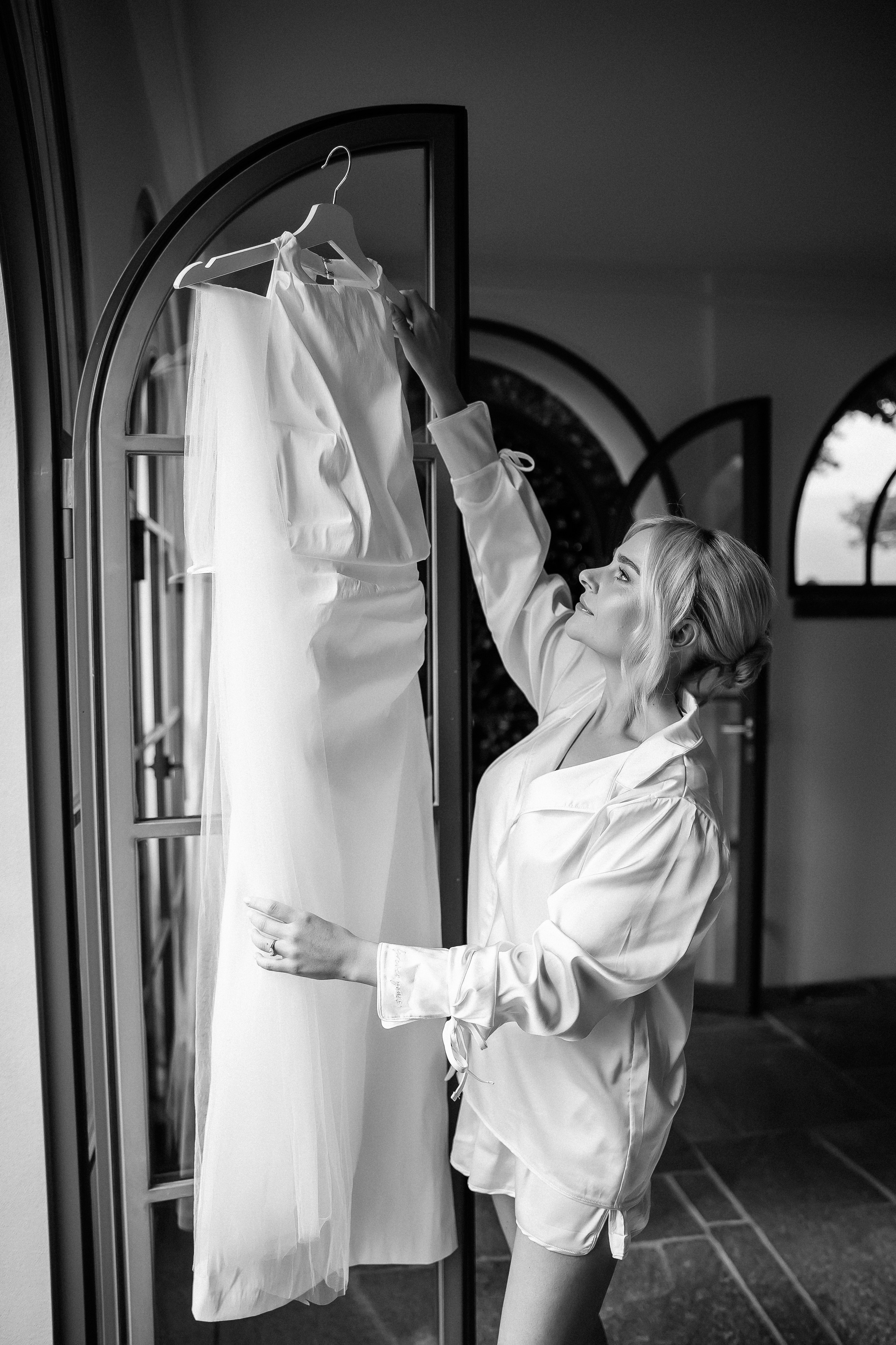 Bride putting on her wedding gown in an arched doorway at Villa Lario, Lake Como, Italy