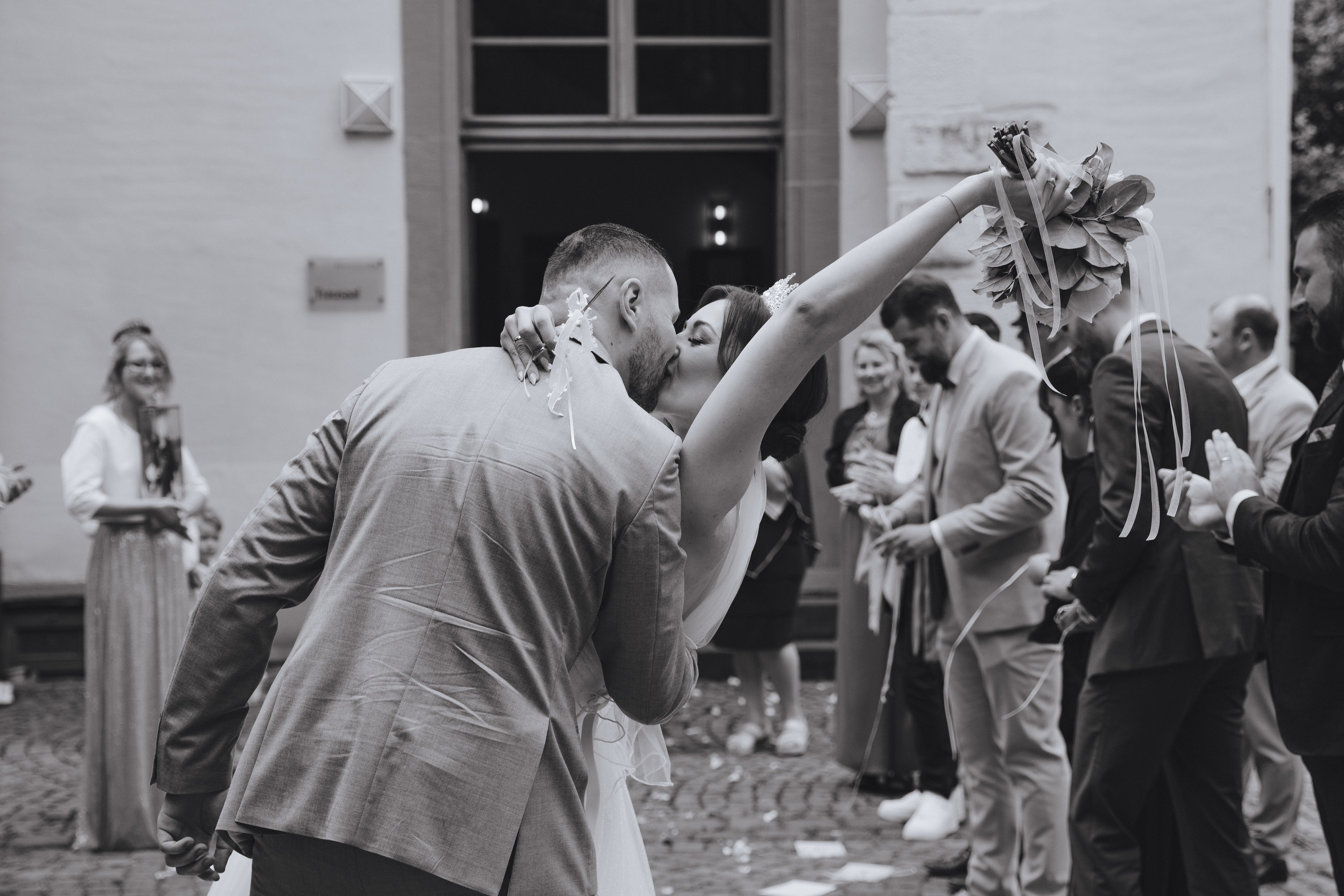Schwarz-Weiß-Foto, auf dem der Bräutigam die Braut küsst. Ein romantischer und intimer Moment der Hochzeit.