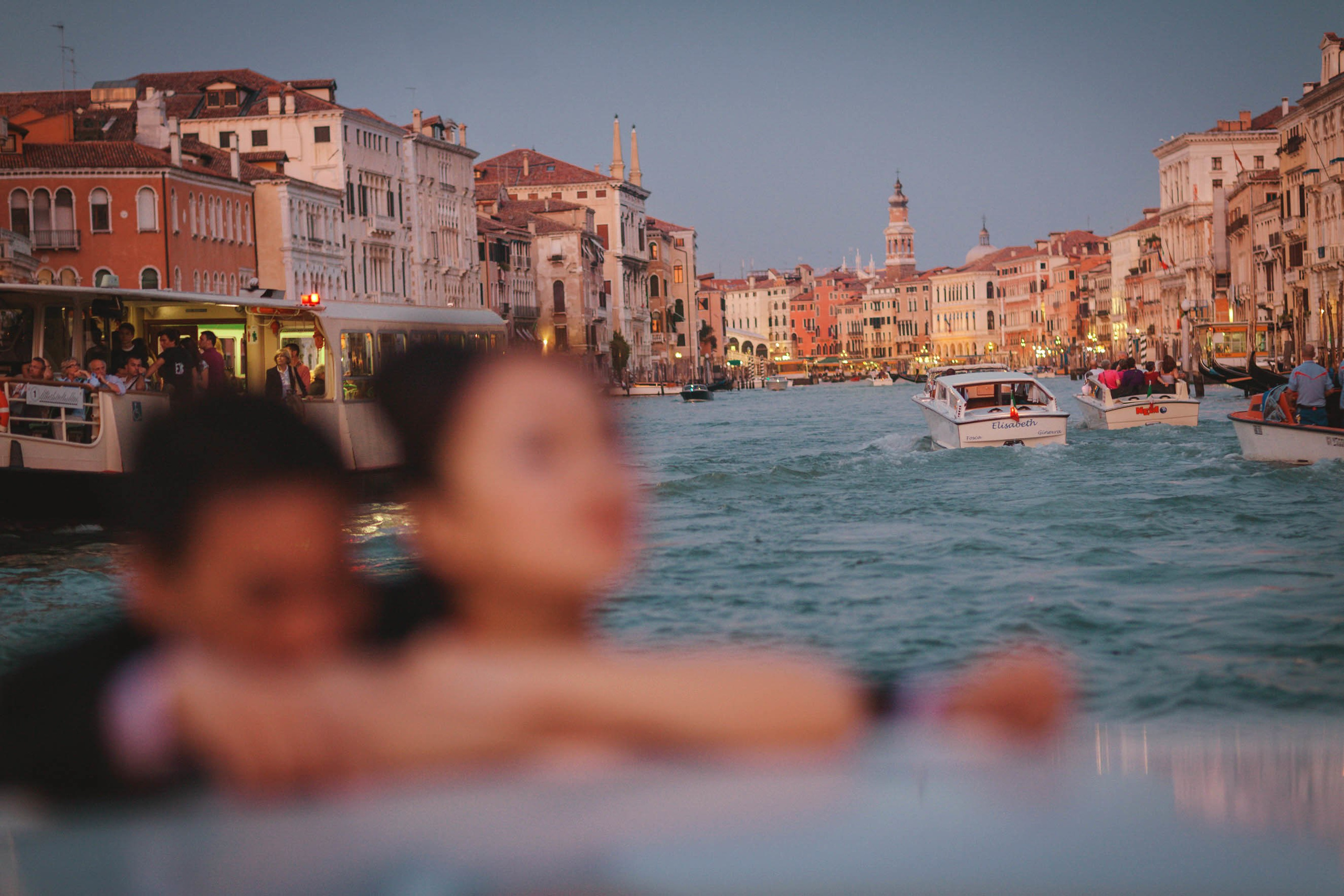 Couple enjoying private boat ride along historic Venice canals at dusk.