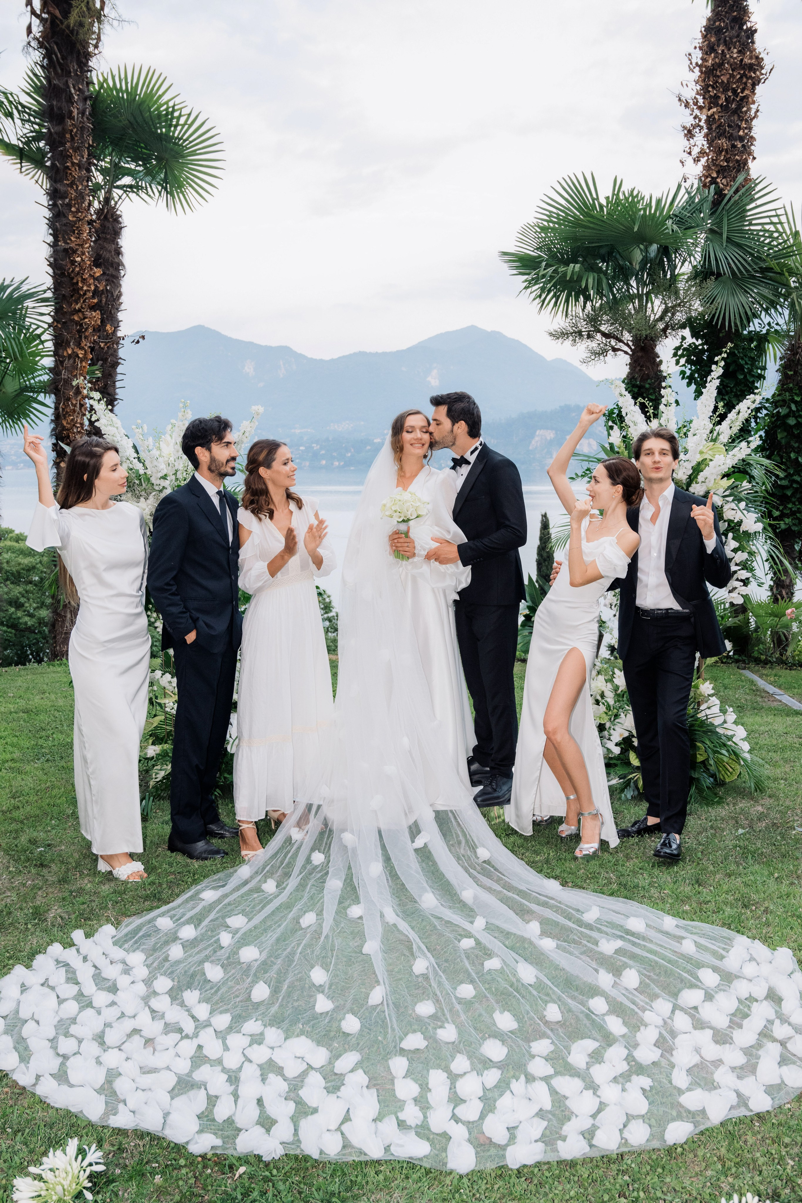 a bride and groom kiss in front of their wedding party