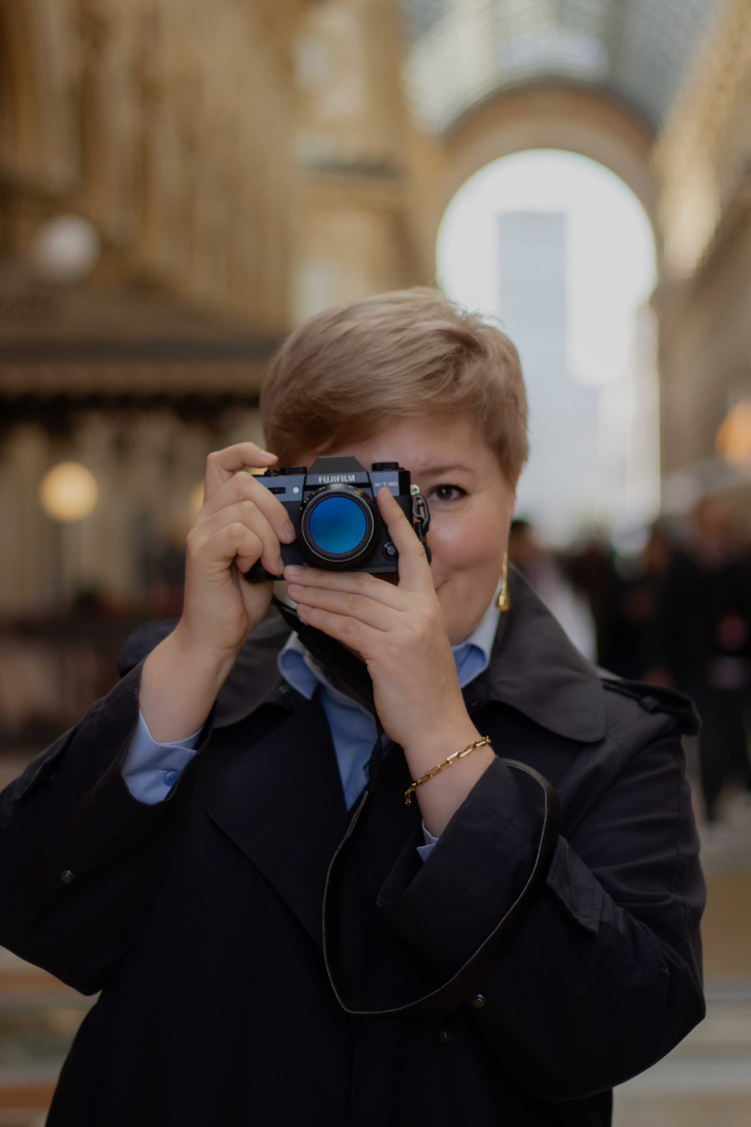 девушка с фотоаппаратом в руке в центре галереи Виктора Эммануила в Милане