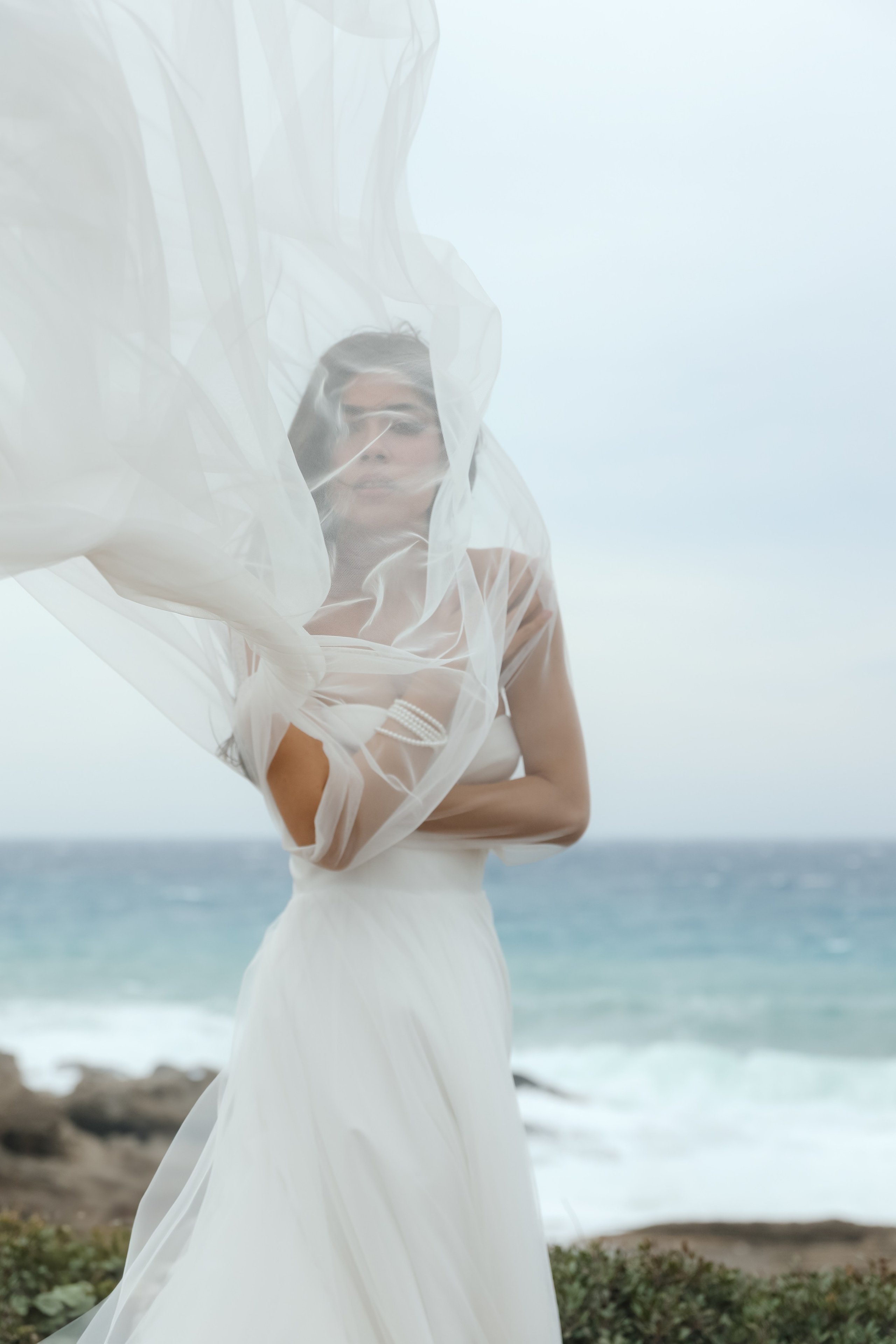 An art photo shoot of a girl in a wedding dress on the windy Kalithea beach in Rhodes, Greece