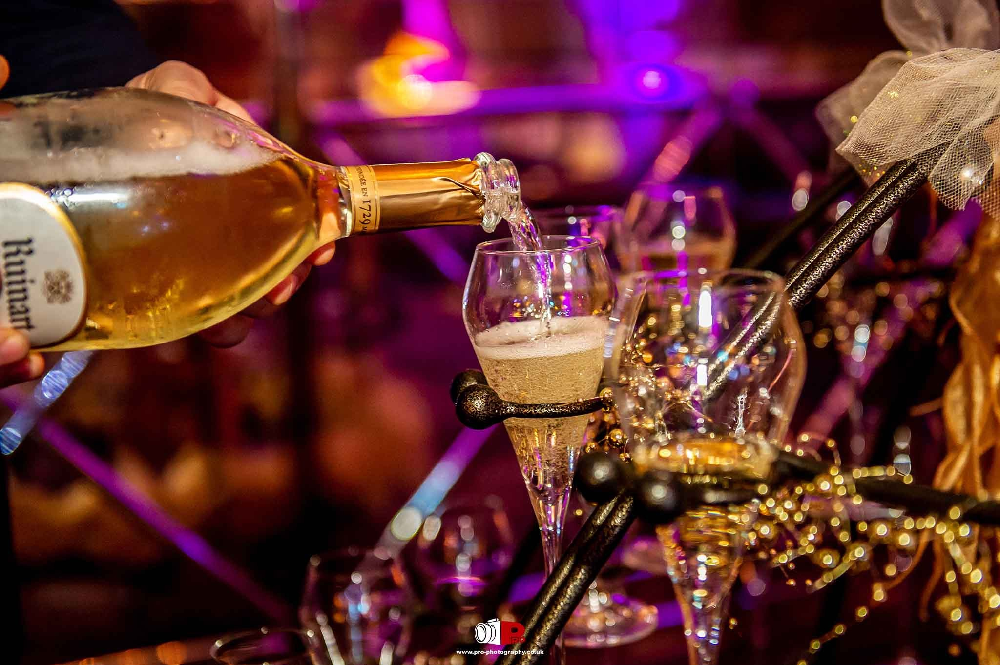 At a luxurious gala celebration, a bottle of Ruinart champagne is poured into an elegant glass.