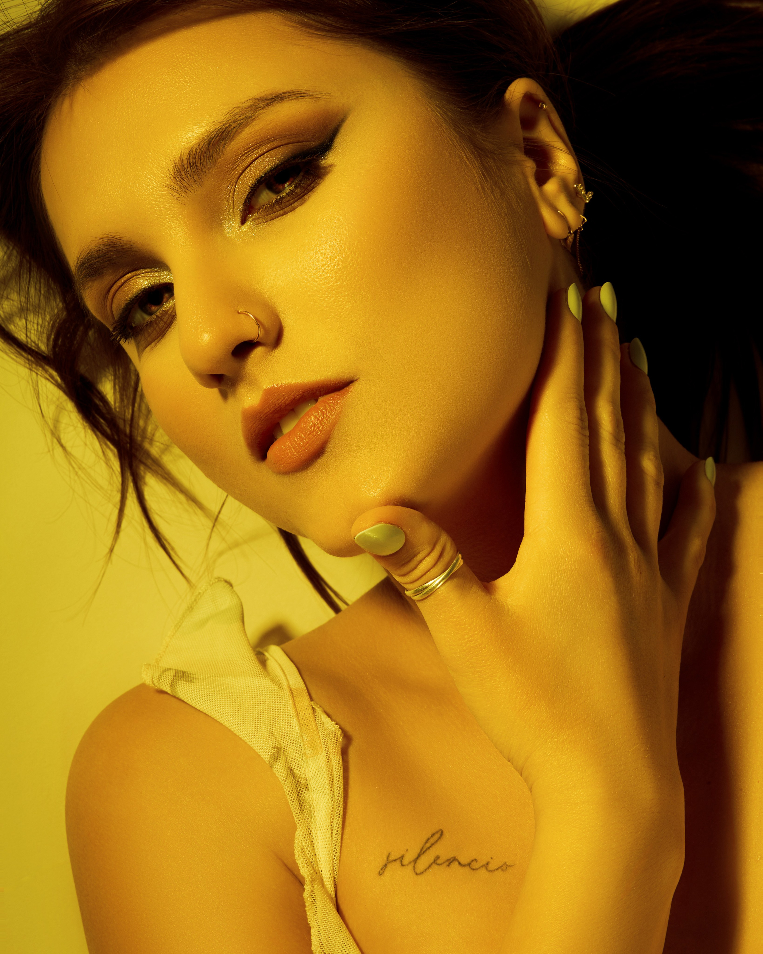 South Jordan studio close-up portrait of a woman in golden light with bold eyeliner and hand on her neck.