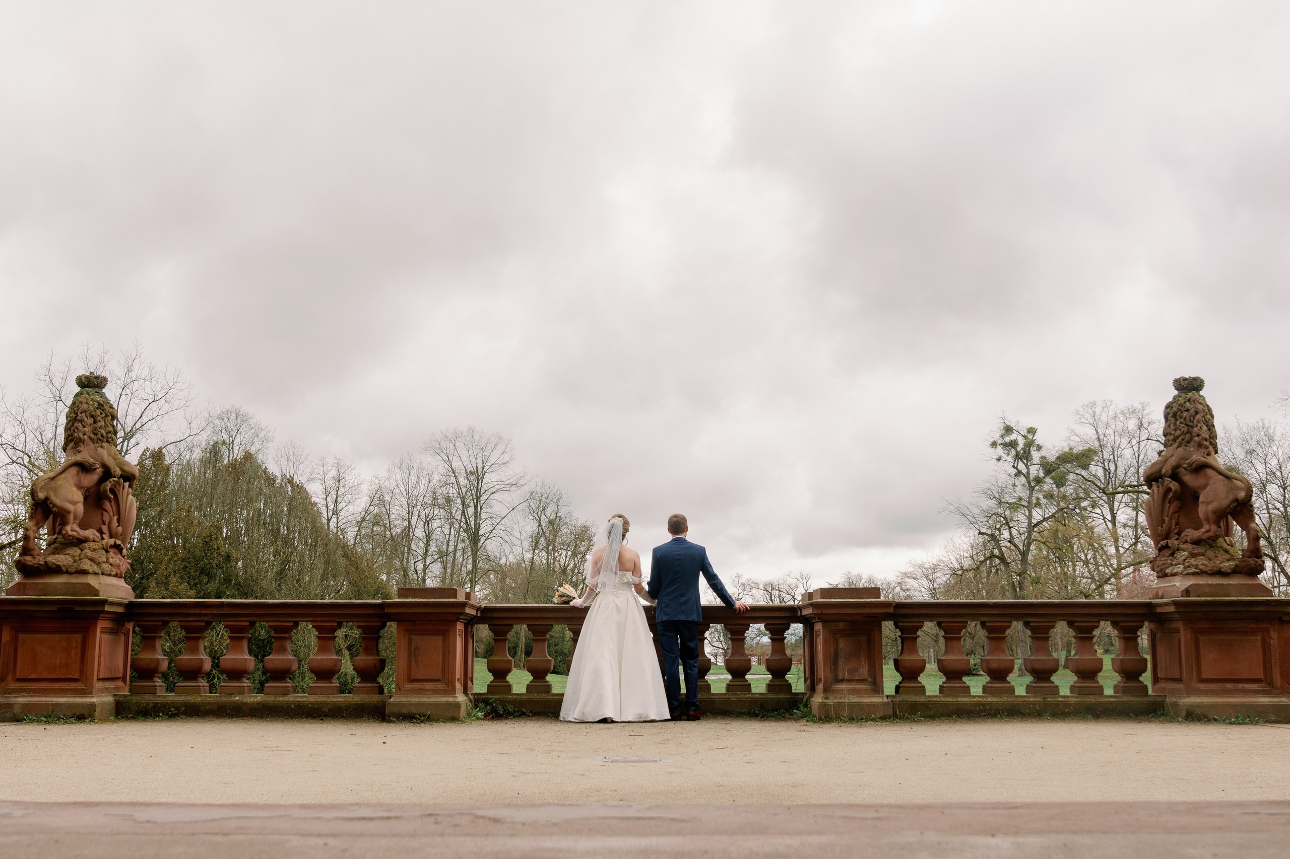 Hochzeitspaar vor dunklen Wolken im Schlosspark Philippsruhe