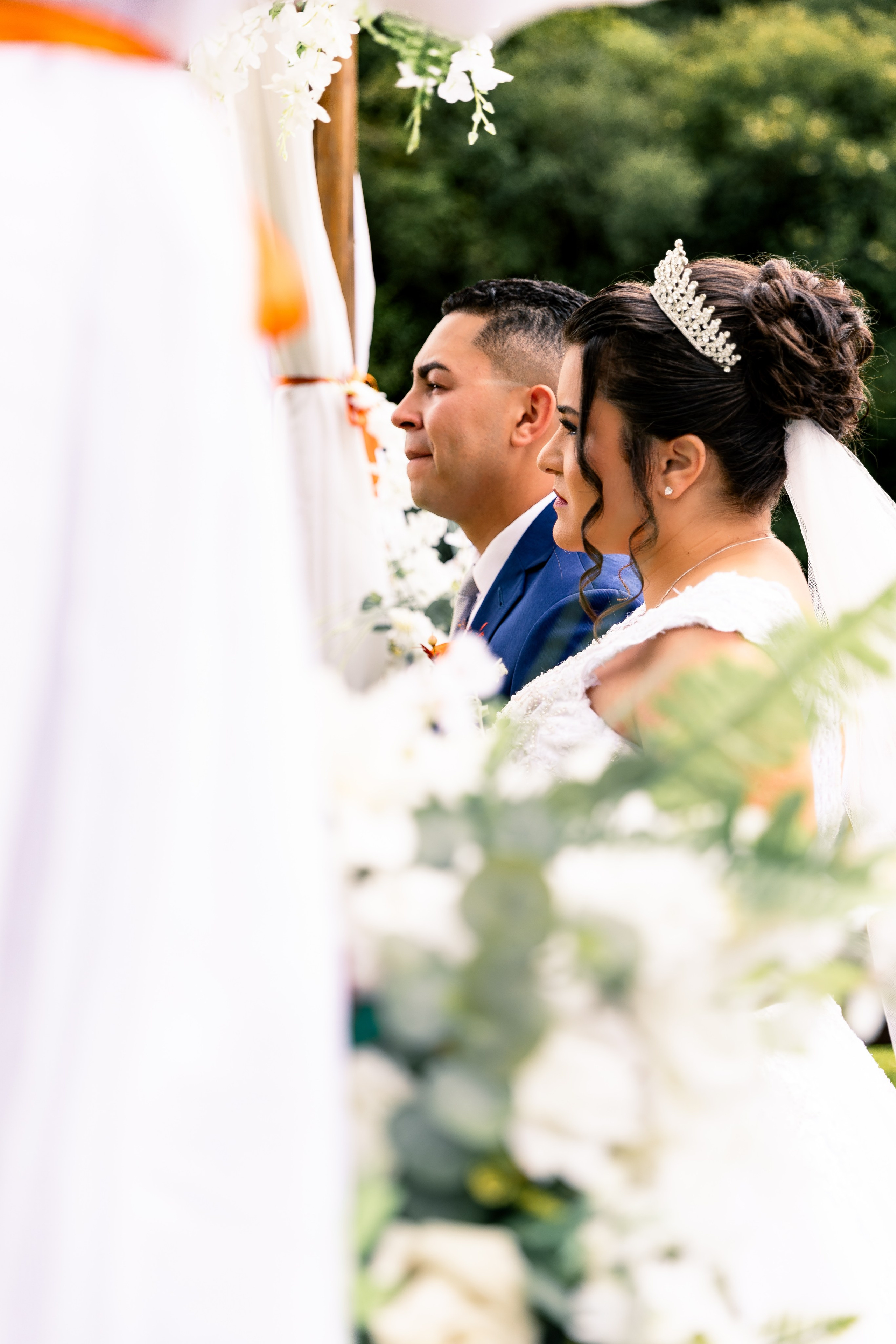 Noiva e noivo lado a lado no altar, ouvindo atentamente o celebrante durante a cerimônia.