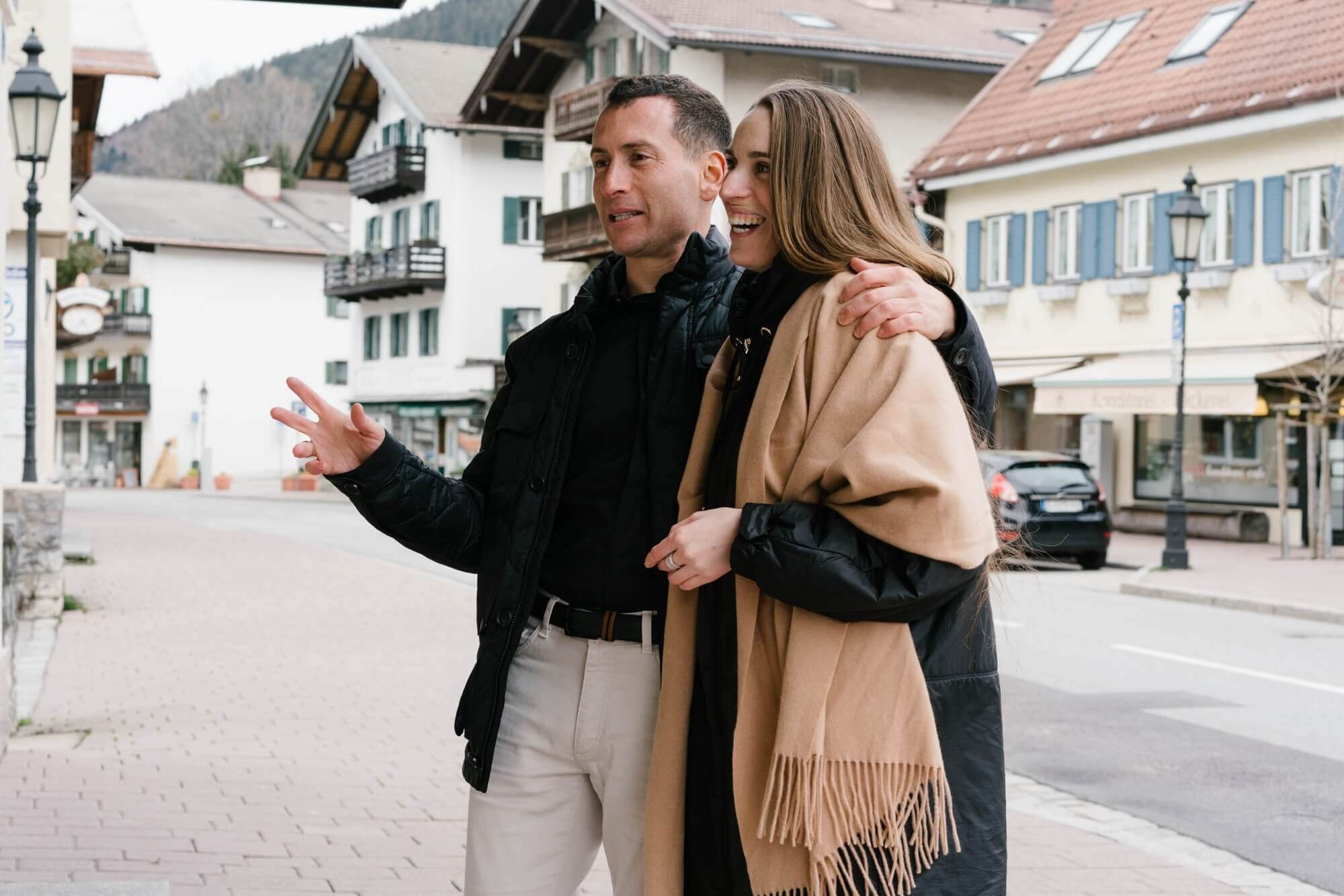 Couple walking on a street in Tegernsee town - man with arm around woman in beige fringe coat during couple session