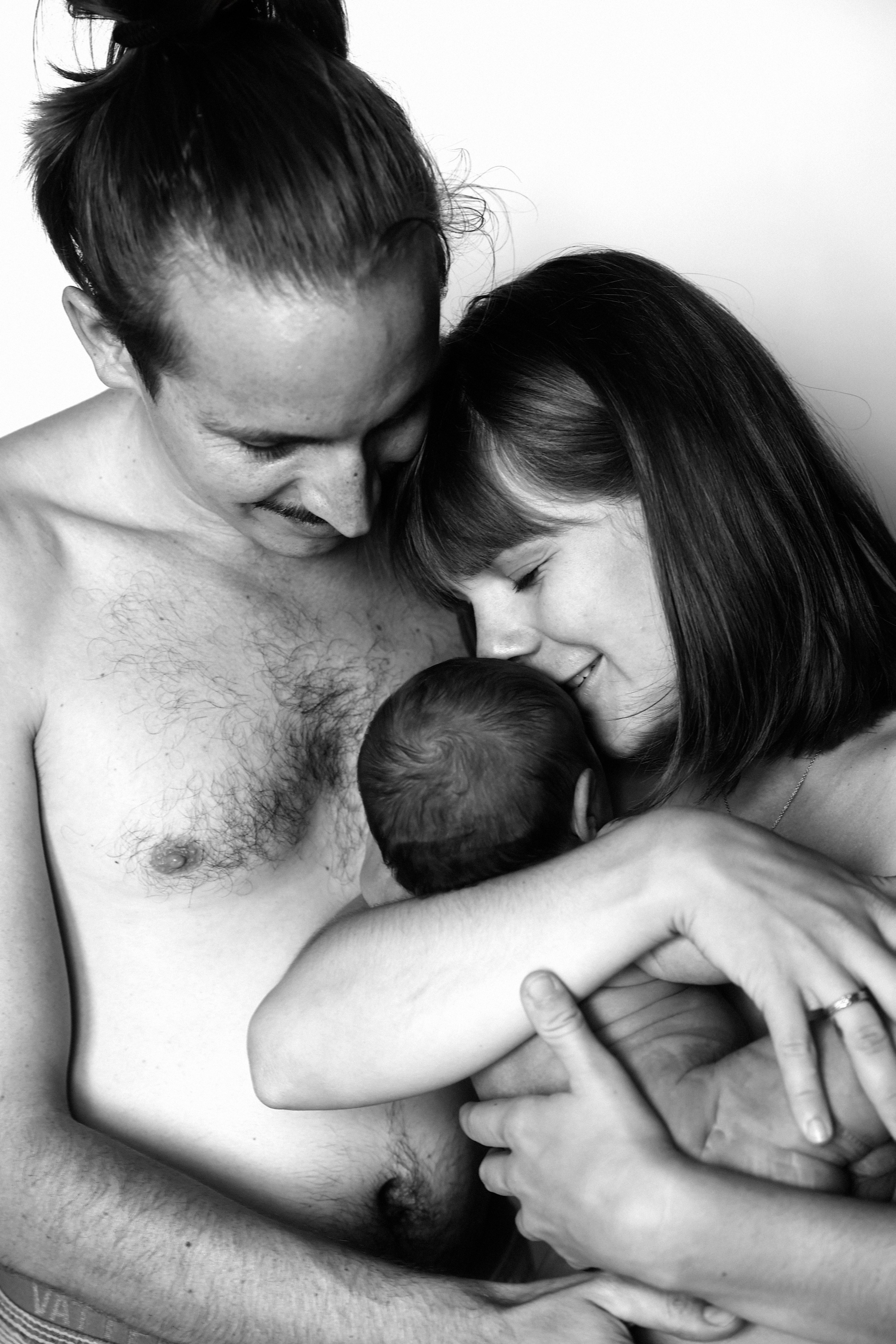 Neugeborenes Baby in den Armen von Mutter und Vater – inniger Familienmoment voller Liebe und Geborgenheit.