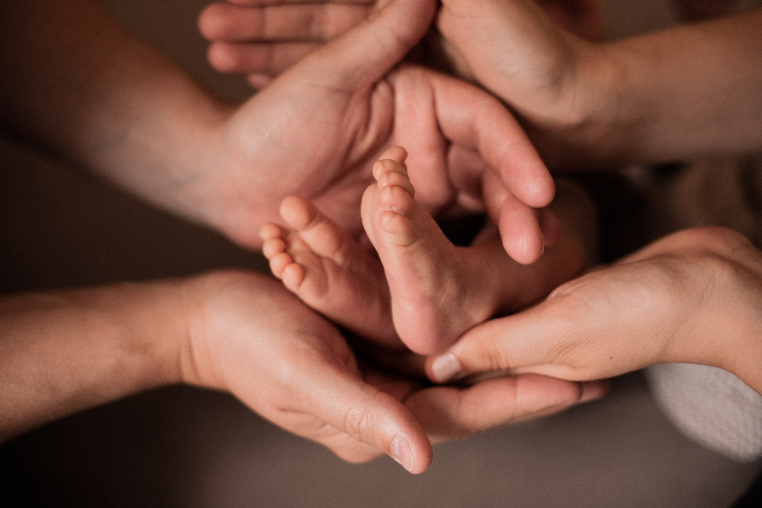 Die Hände von Mama und Papa umarmen die Füße des Neugeborenen.