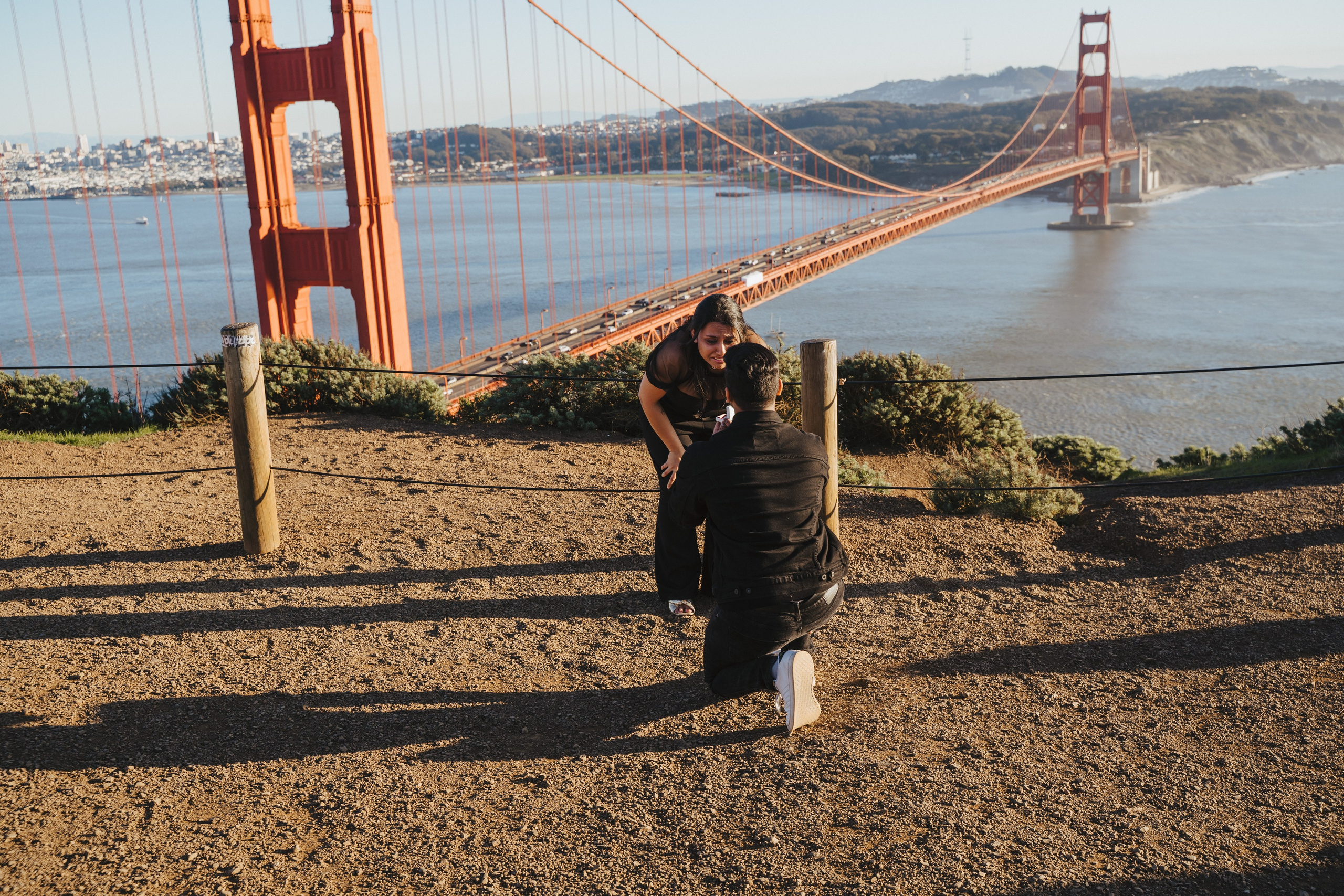 Proposal.  Overlooking the golden San Franisco Bridge sunset with a couple. Photographer Video. 