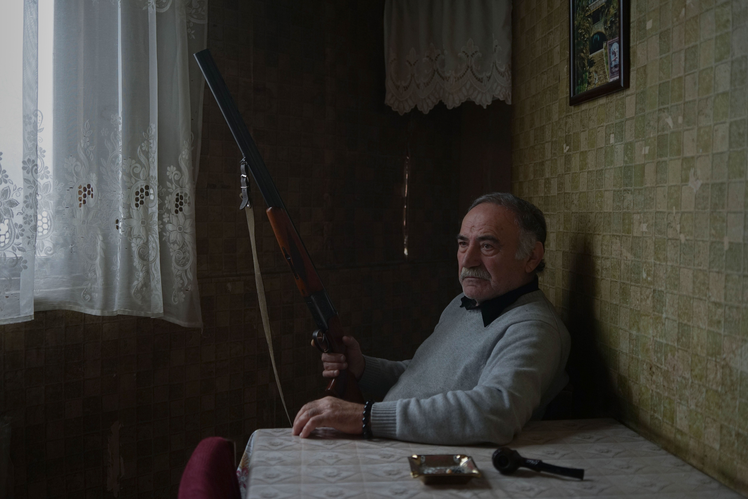 Oscar with a captured rifle in his hands in his kitchen in the former sanatorium ”Aia”. When the war began, Oskar persuaded his family to leave Gagra, and he himself remained to guard the house. He did not want to fight and hoped that the conflict would end quickly and everything would return to normal. When his sister was killed, he took a gun. In Sukhumi, his squad received a tip on a war criminal, when they entered his house, they found a weapons depot. Oscar took one of the guns as a trophy. Later he was shot in the head and taken to Georgia for treatment. He was helped to escape and leave the war zone by his friend, the Abkhaz.