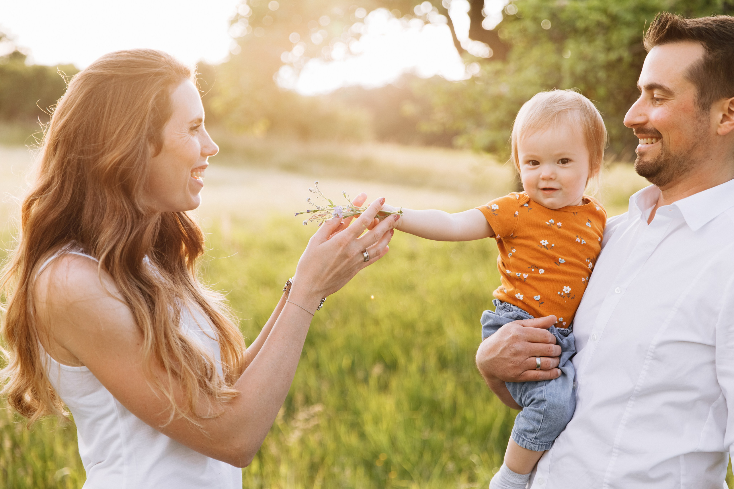Familienmoment auf der grünen Wiese: Mama und Papa genießen den Tag mit ihrer kleinen Tochter.