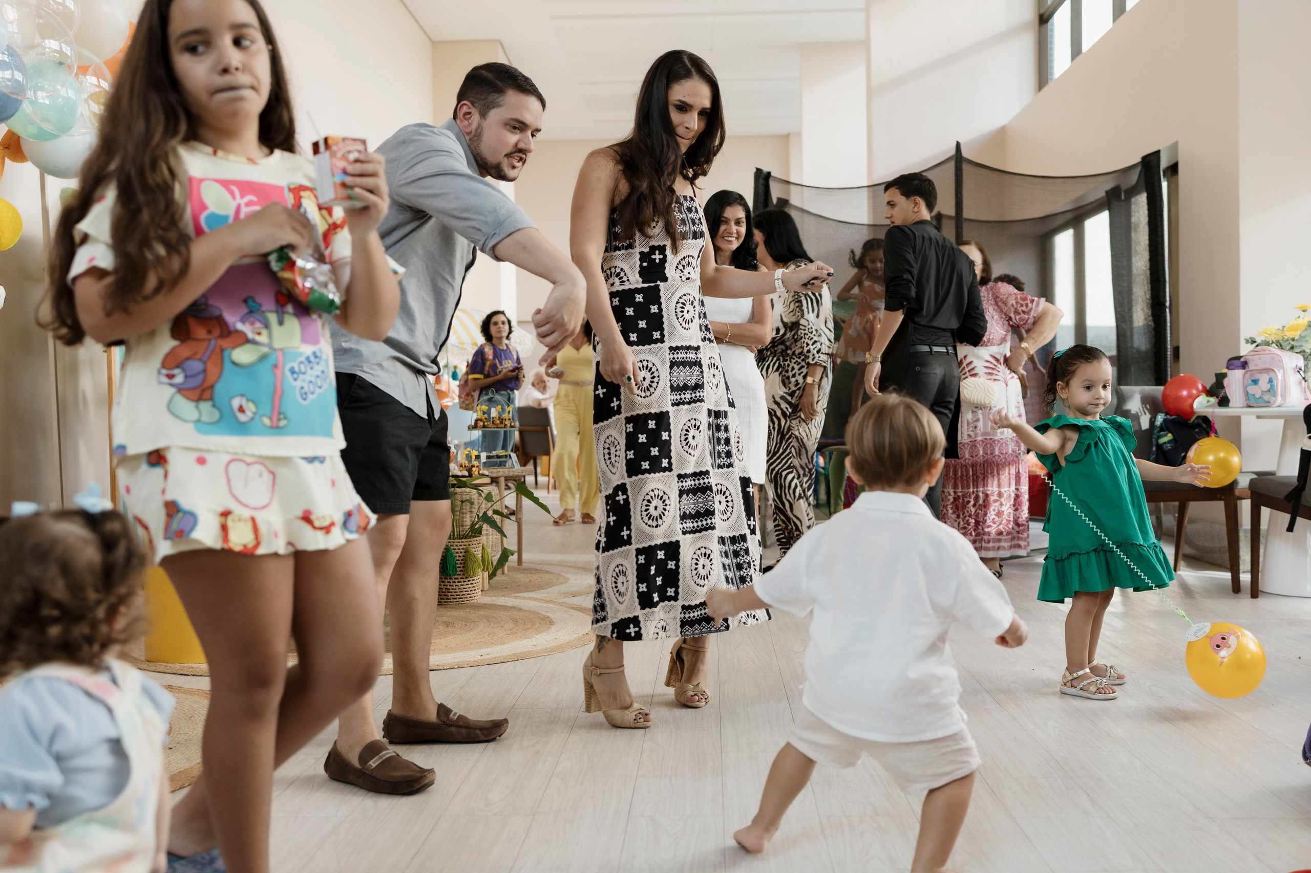 Criança de dois anos dançando e aproveitando a festa com os pais e convidados