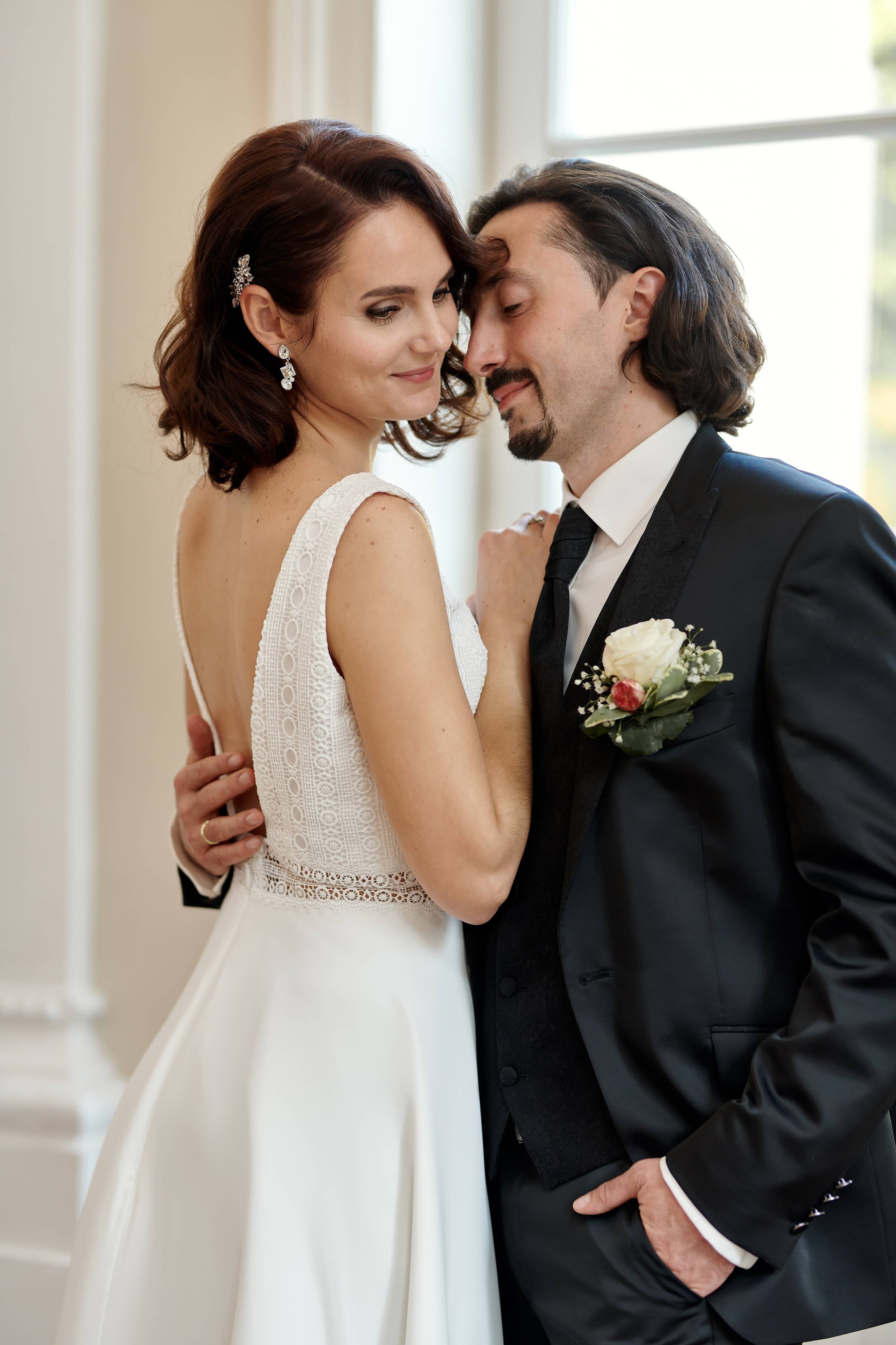 Zärtlicher Moment zwischen Alexej & Katja bei ihrer standesamtlichen Hochzeit in der Villa Eugenia in Hechingen – innige Nähe am Fenster im natürlichen Licht.